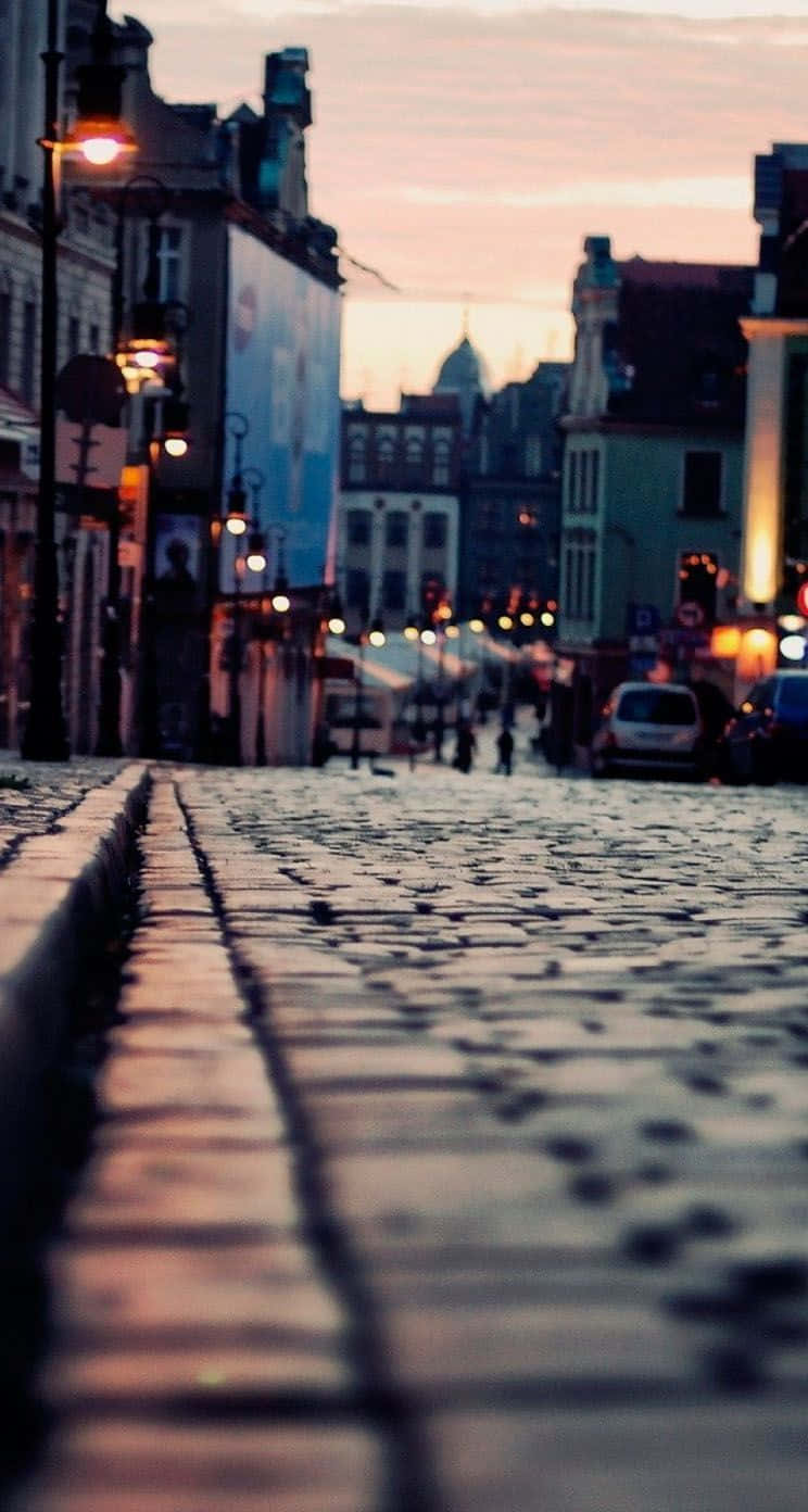 黃昏時分的鵝卵石街道，帶有模糊的路燈和歷史建築。