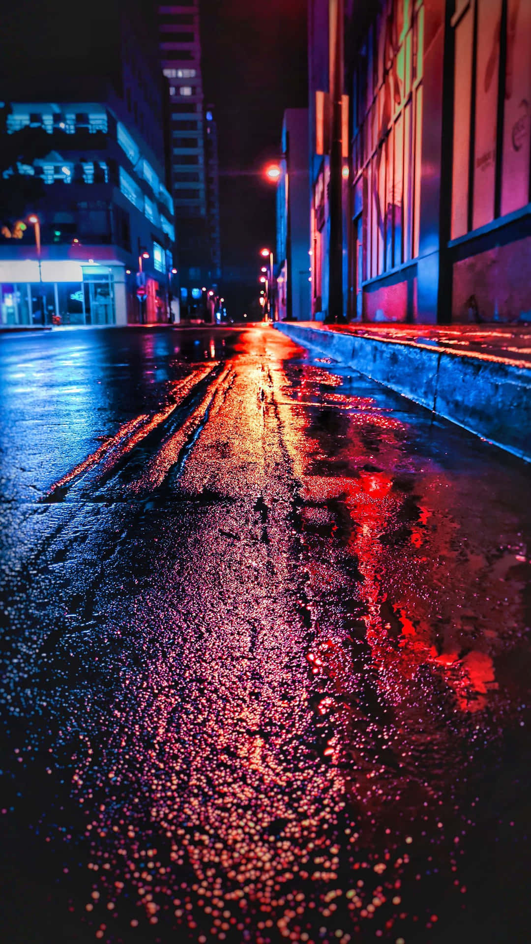霓虹燈光在夜間城市街道的濕漉漉路面上反射。