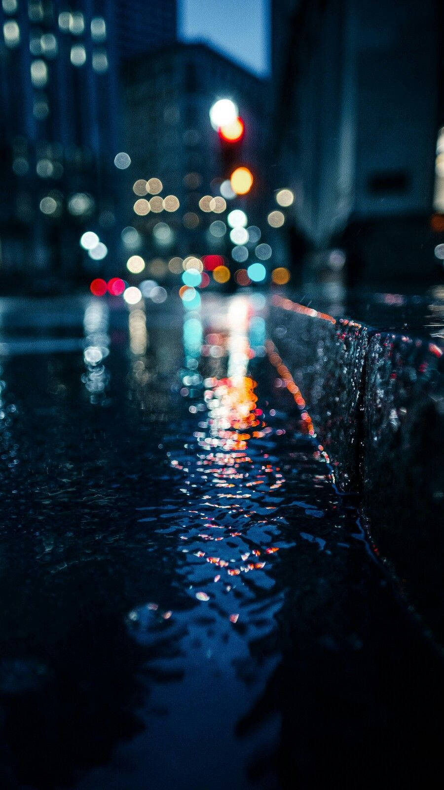 雨夜城市街道，水坑中反射著模糊的燈光。