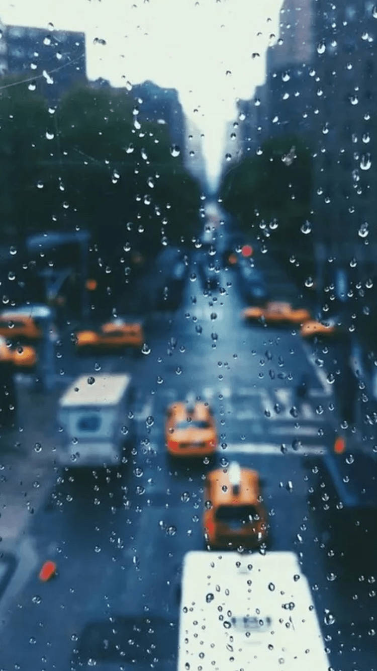 窗戶上的雨滴，俯瞰著一條有黃色出租車的城市街道。