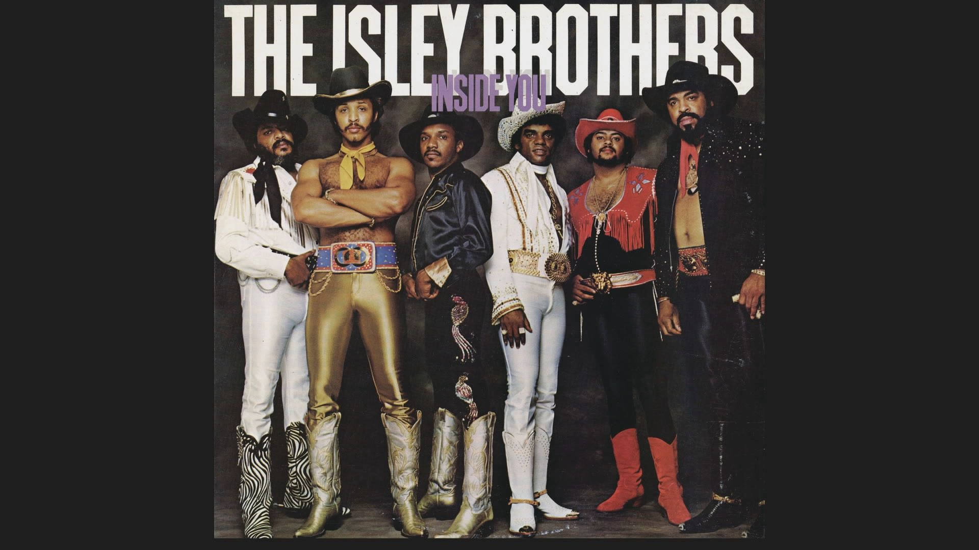 Isley Brothers《Inside You》專輯封面 壁紙 — The Isley Brothers 在深色背景前自信地擺姿勢，穿著閃亮的70年代牛仔風格服裝，飾有亮片和寬邊帽。