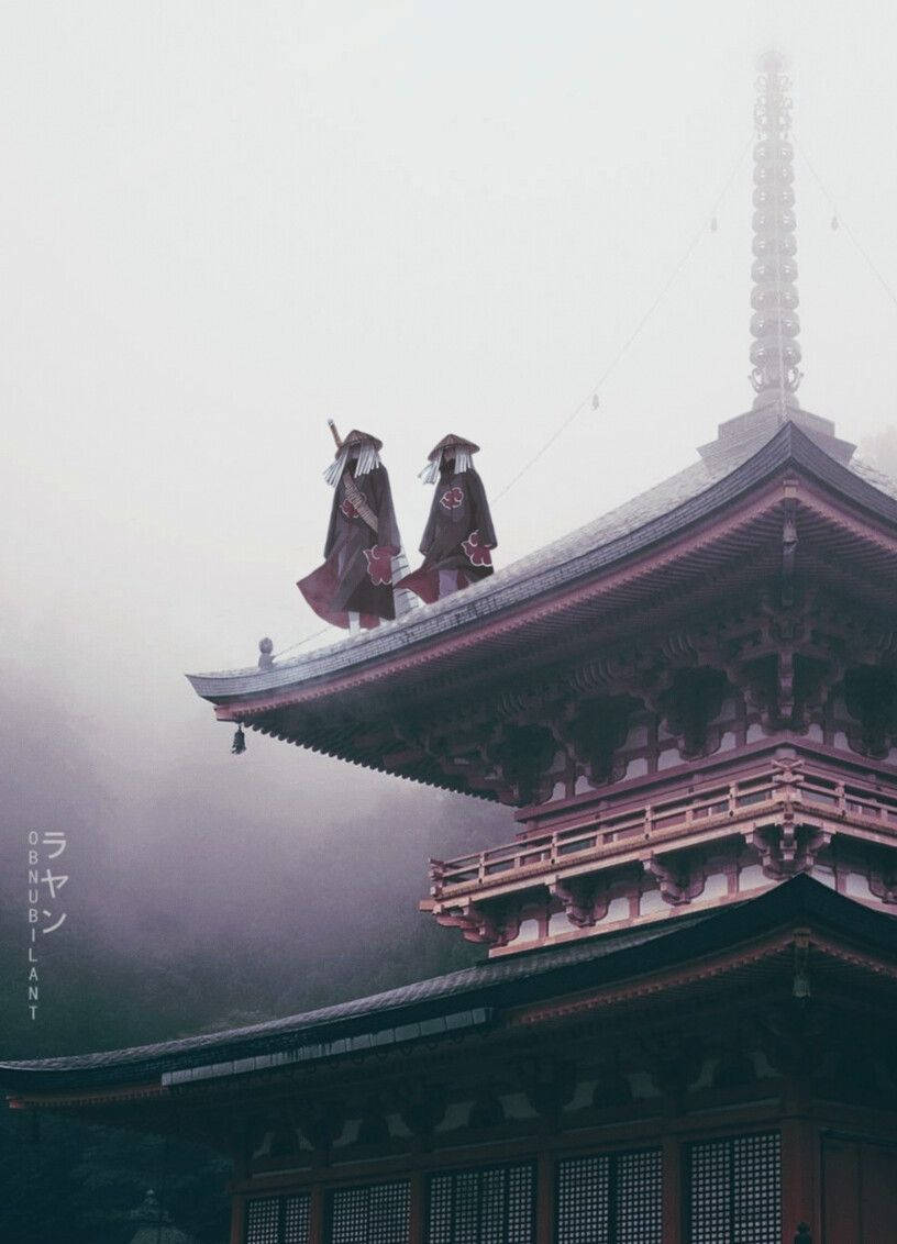 兩個身穿長袍的人物在霧氣籠罩的寺廟屋頂上。