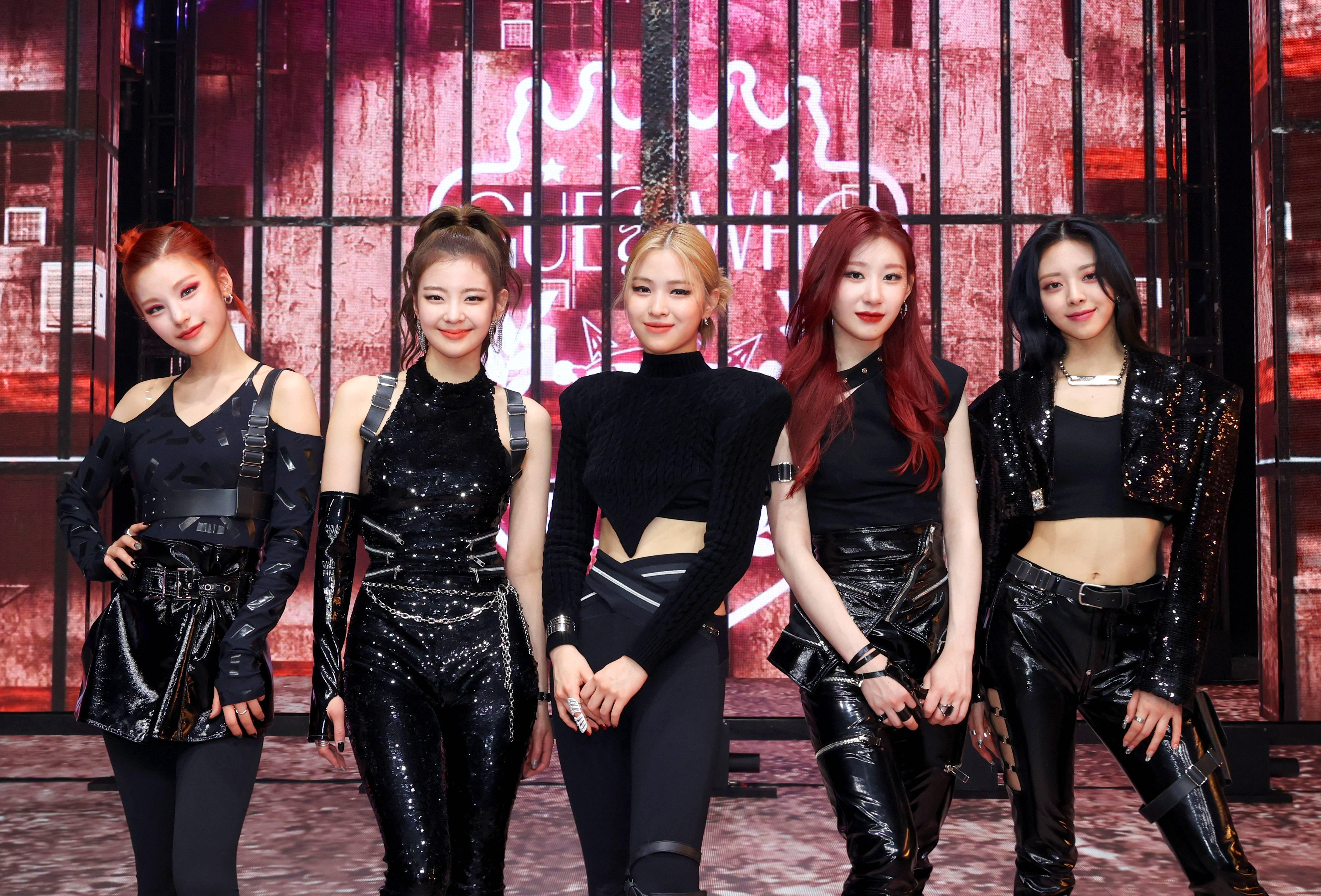 ITZY《Mafia In The Morning》舞台展示 壁紙 — 五位時尚的女表演者穿著黑色亮片服裝，在紅色霓虹燈照亮的城市背景下自信地擺姿勢。