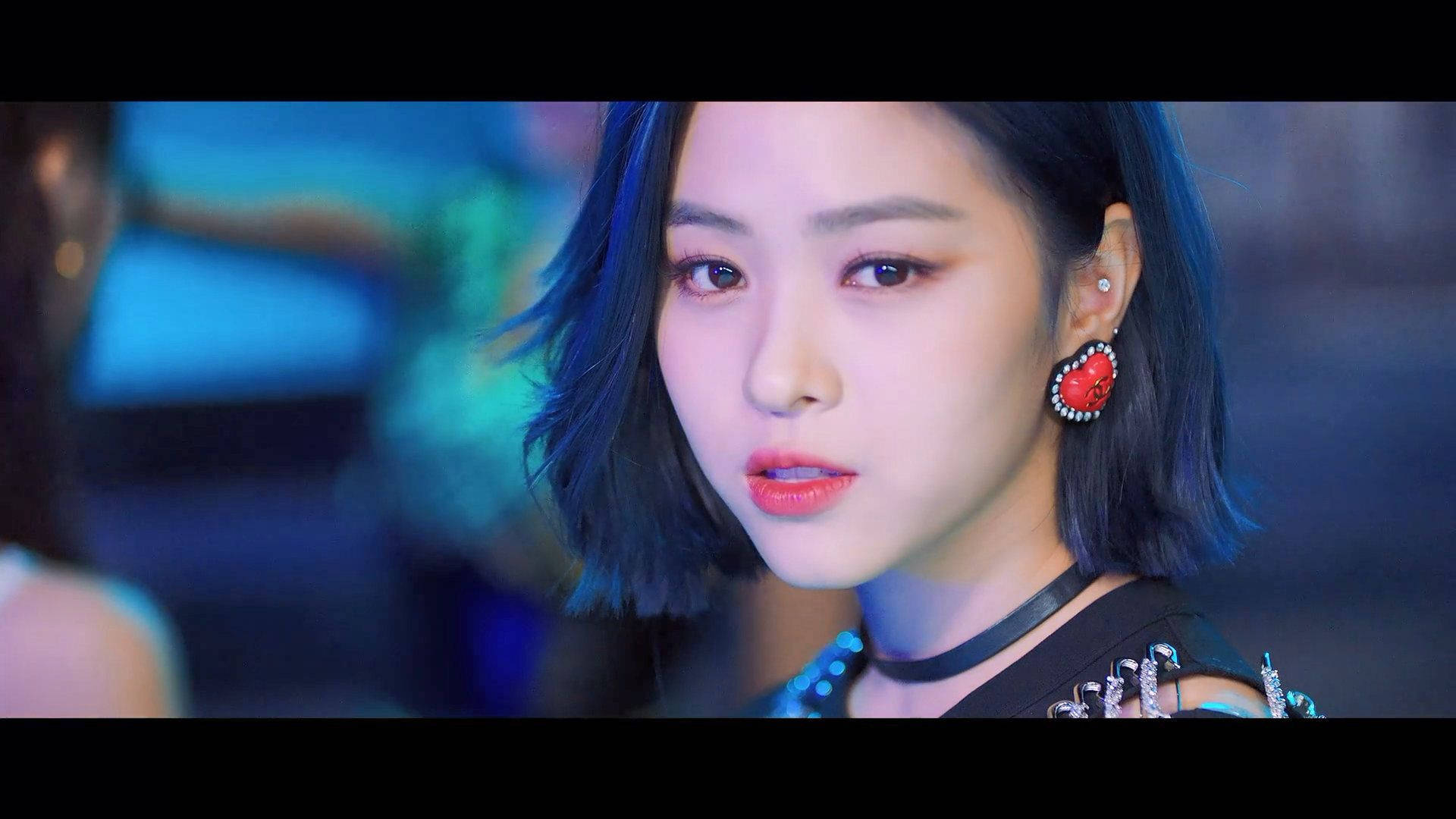 ITZY 申留真藍髮造型 壁紙 — 年輕女性特寫，短藍色頭髮，大膽紅色唇膏，在冷藍色舞台燈光下。