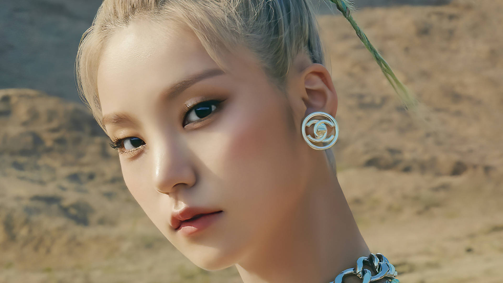 ITZY 黃藝智 壁紙 — 一個金髮女子嘅特寫肖像，化咗大膽妝容，背景係陽光普照嘅沙漠。