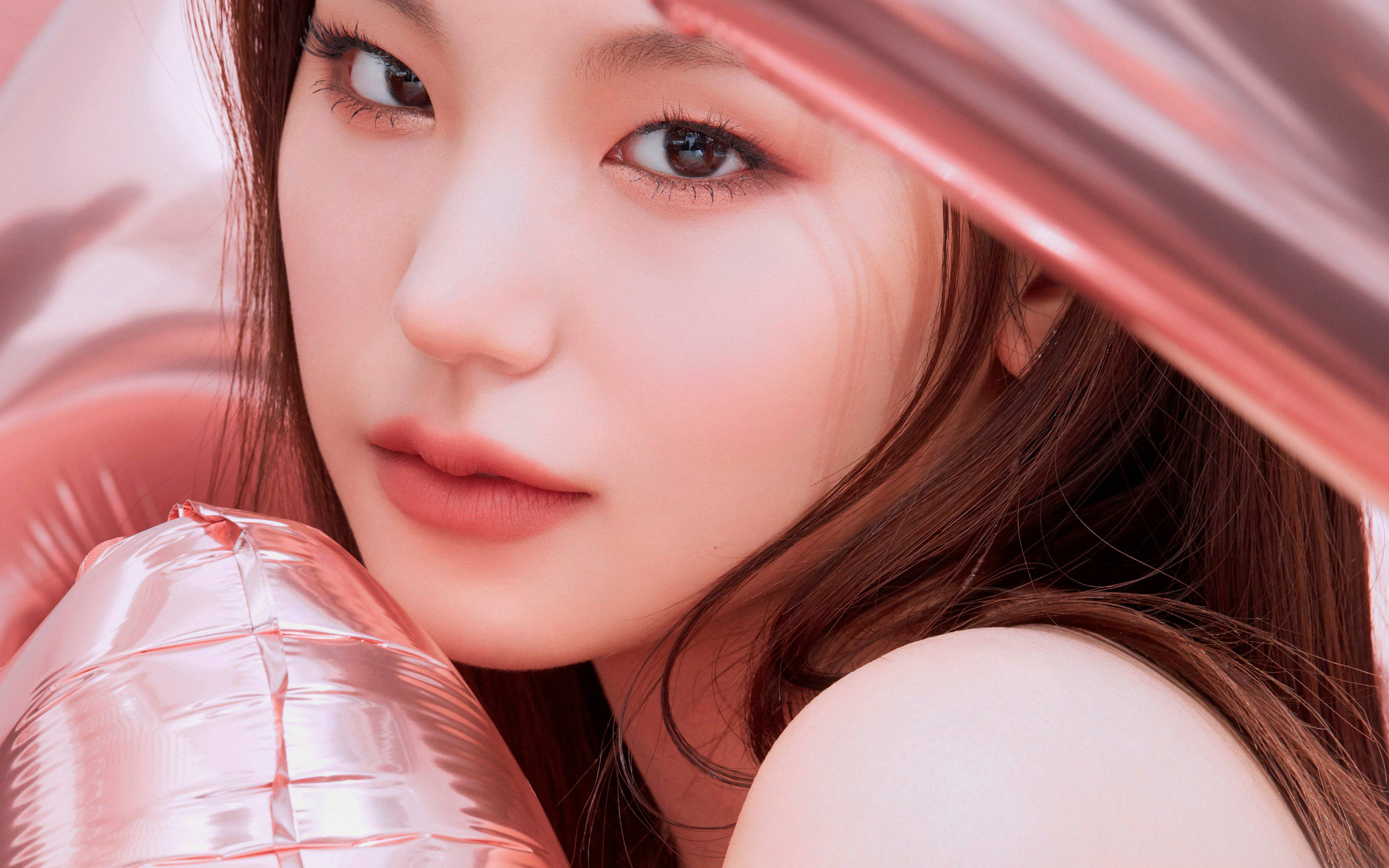 ITZY 黃藝智美學 壁紙 — 一位年輕女性的特寫肖像，妝容柔和，棕色頭髮，部分被閃亮的粉紅色氣球遮擋，背景為相配的粉紅色。