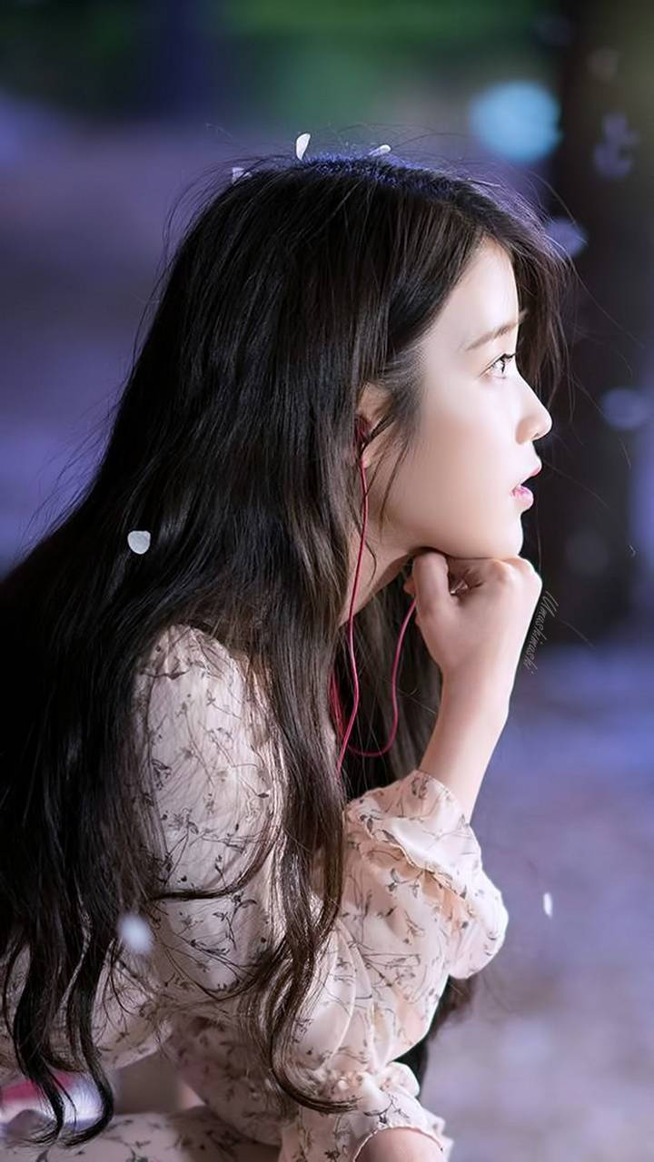 年輕女性在夜間戶外用紅色耳機聽音樂。