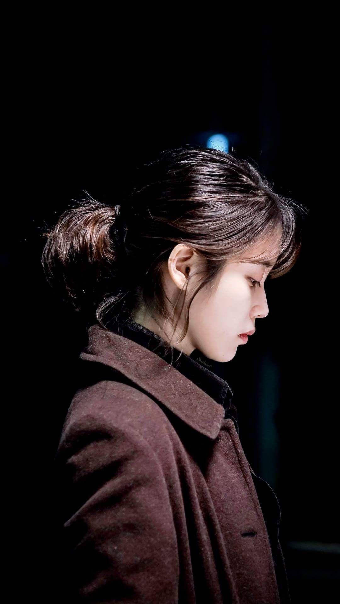 身穿棕色外套的女性在昏暗光線中低頭