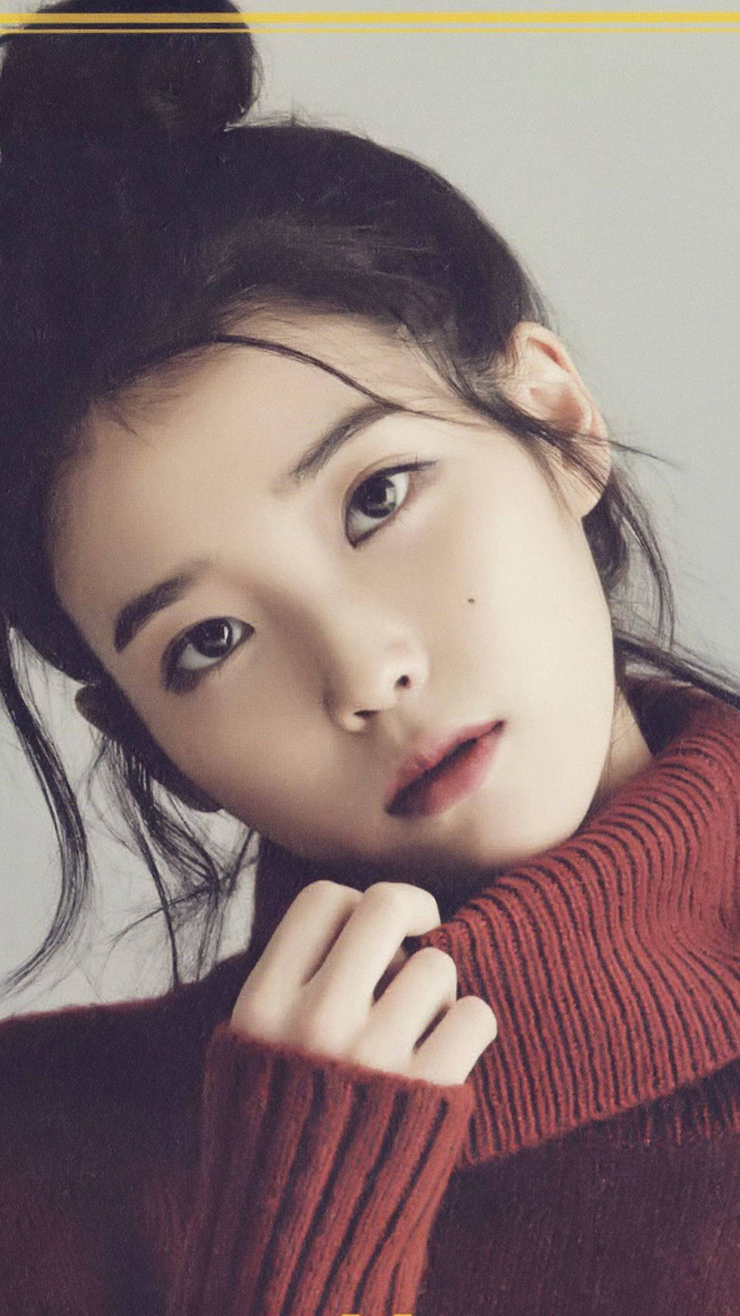 IU紅色高領外套 壁紙 — 一位深色頭髮束成髮髻的年輕女性，將下巴擱在紅色羅紋毛衣上，溫柔地凝視著。