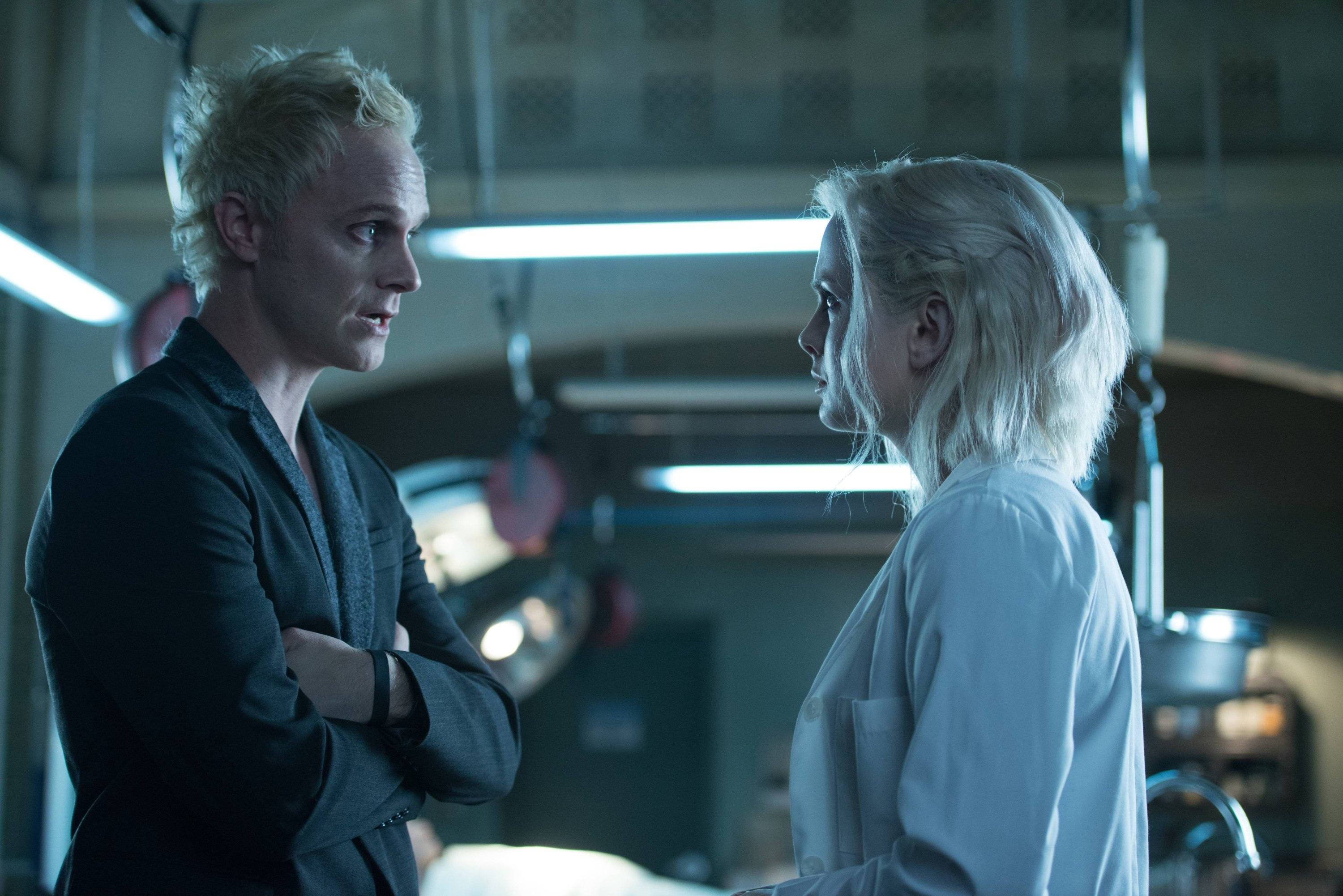 《iZombie》莉芙·摩爾與布萊恩·德比爾斯共享美好時光 壁紙 — 兩位淺色頭髮嘅人喺一個無菌、螢光燈照明嘅醫療室入面，頭頂有手術設備，互相對峙。