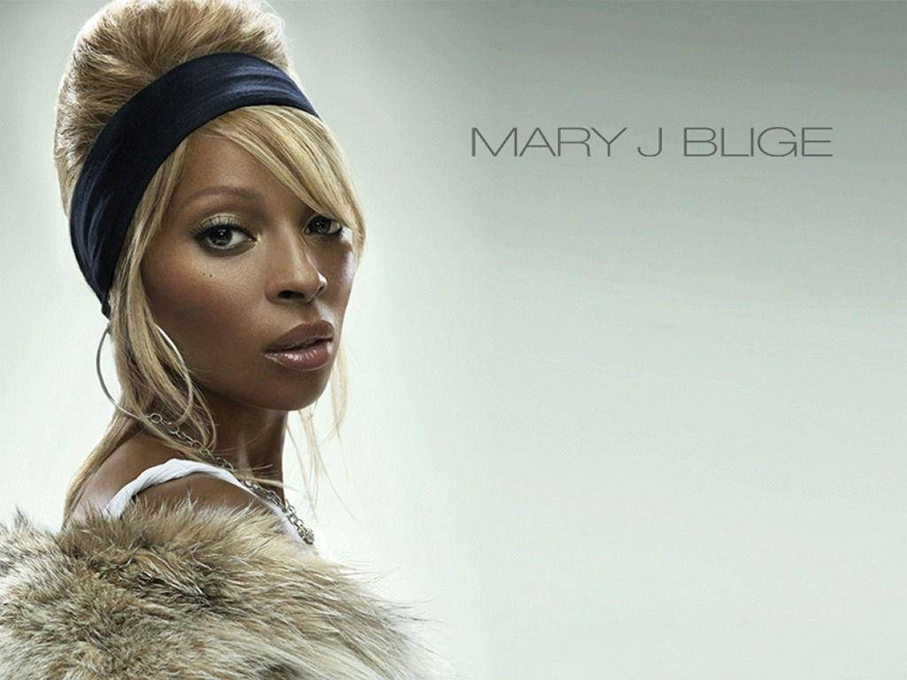 美國創作歌手瑪麗·J·布里吉 壁紙 — Mary J Blige 專注地凝視，毛皮修飾的肩膀在純灰色背景上清晰可見。