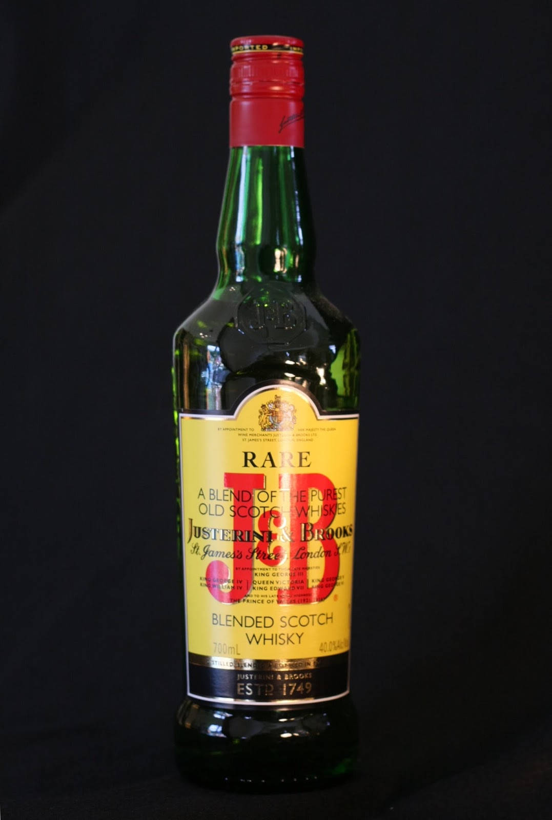 J&B Rare 威士忌瓶配黑色背景 壁紙 — 一瓶綠色玻璃瓶的Justerini & Brooks Rare Blended Scotch Whisky，在黑色背景前，帶有紅色瓶蓋和黃色標籤。