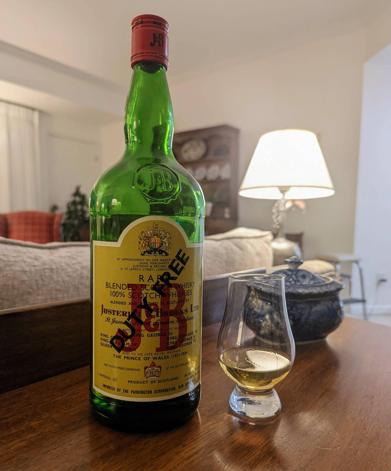 舒適客廳的木桌上放著一個綠色威士忌酒瓶和品酒杯。