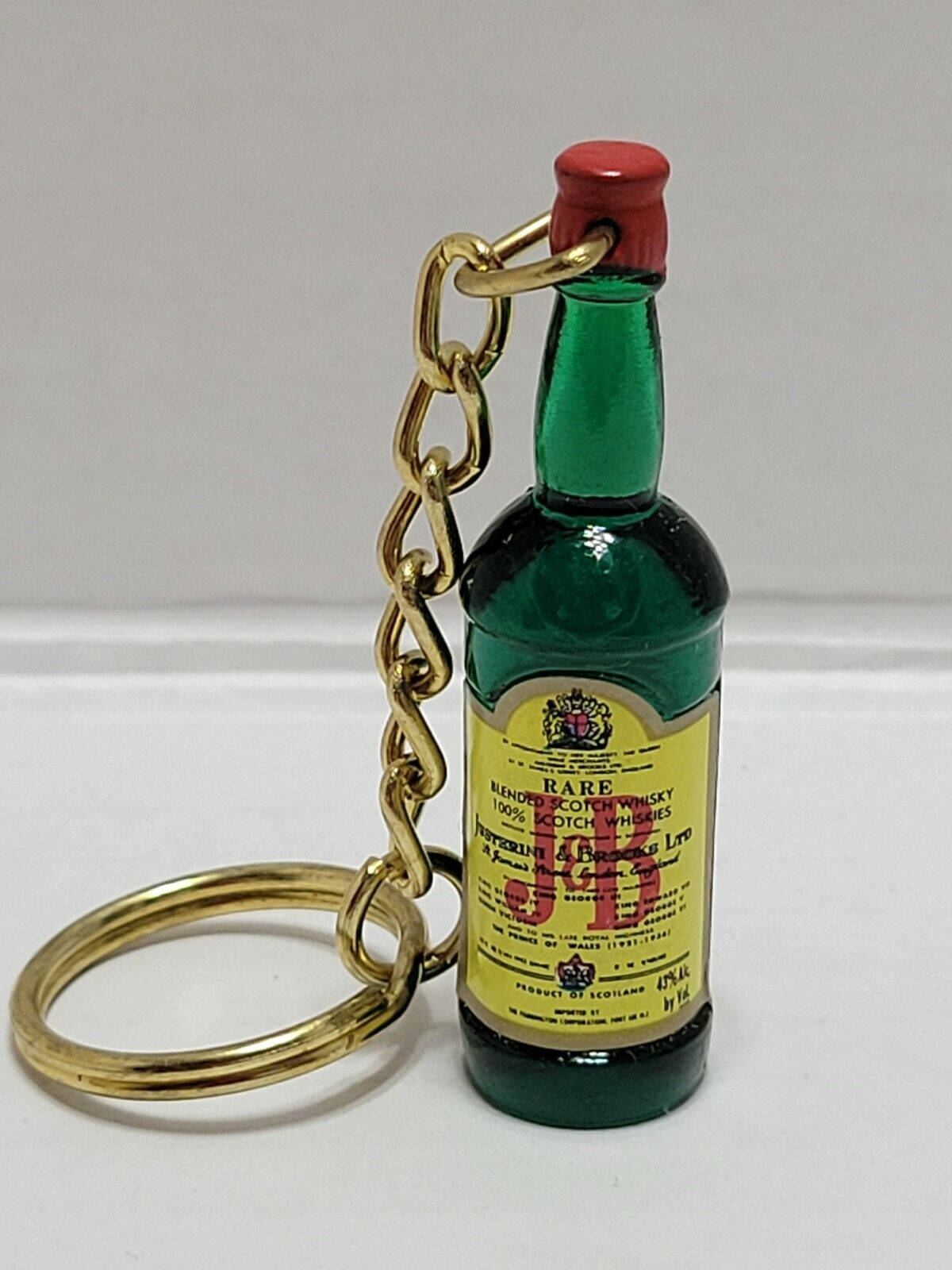 帶有金色鏈條和紅色蓋子的迷你綠色威士忌酒瓶鑰匙扣。
