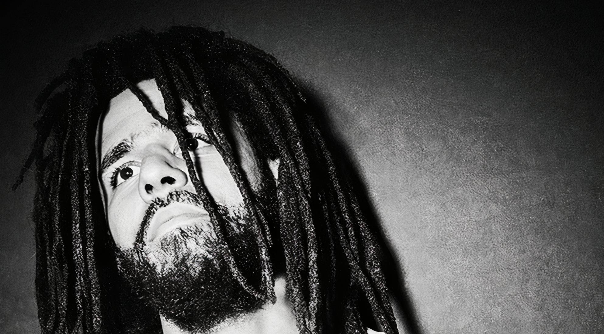 J Cole 長髮造型 壁紙 — 一個黑白特寫肖像，一名留著長辮子和鬍鬚的男子，眼神強烈地向上看。