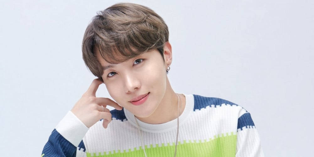 J-Hope 穿條紋上衣 壁紙 — 一位棕色頭髮、帶著溫柔微笑的年輕男子，穿著彩色條紋毛衣，在純白背景前擺姿勢。