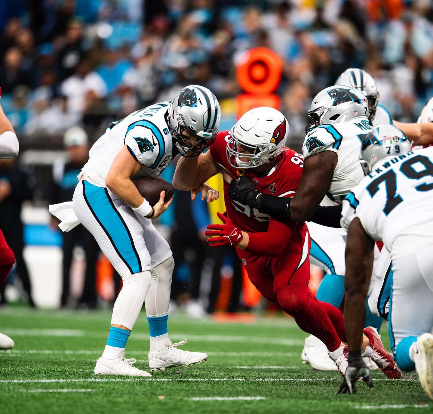 NFL四分衛在日間比賽中於草地場上躲避擒抱。