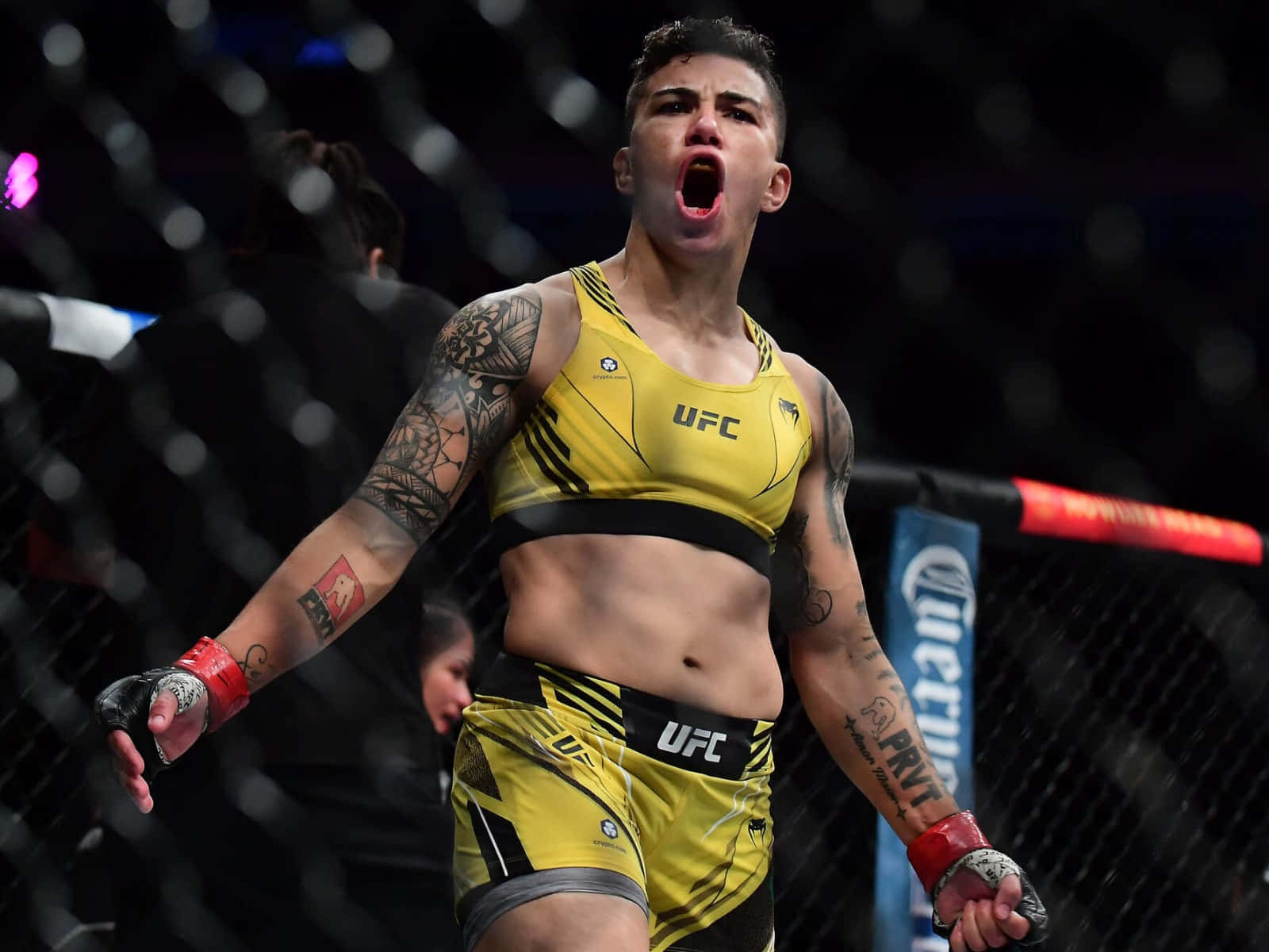 女性MMA拳手在UFC八角籠中張開雙臂慶祝勝利。