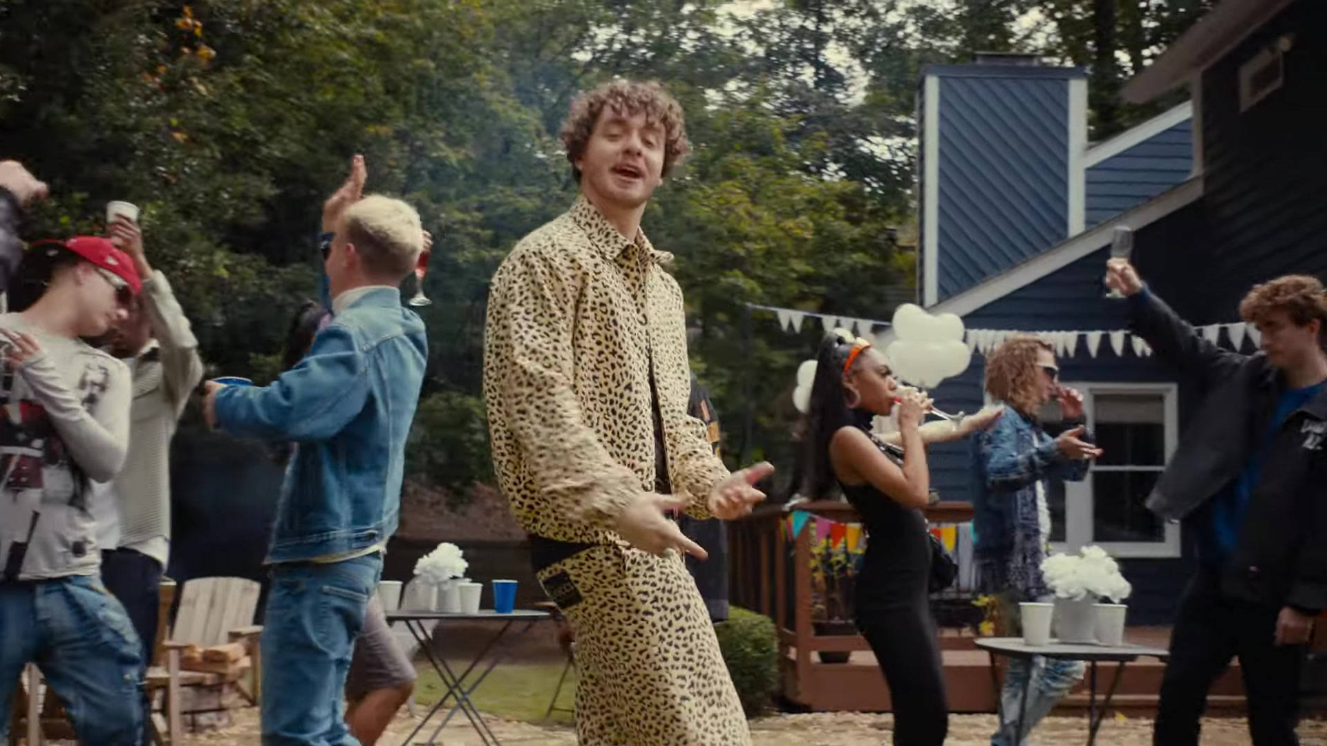 Jack Harlow 在派對 壁紙 — 一群年輕人在樹下的後院派對中充滿活力地跳舞，背景是一座藍色的房子。