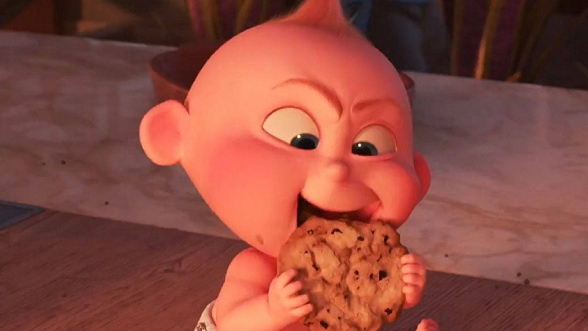 Jack Jack 餅乾 壁紙 — 一個胖嘟嘟的動畫嬰兒，睜大眼睛，坐在木地板上，急切地咬著一塊朱古力曲奇。