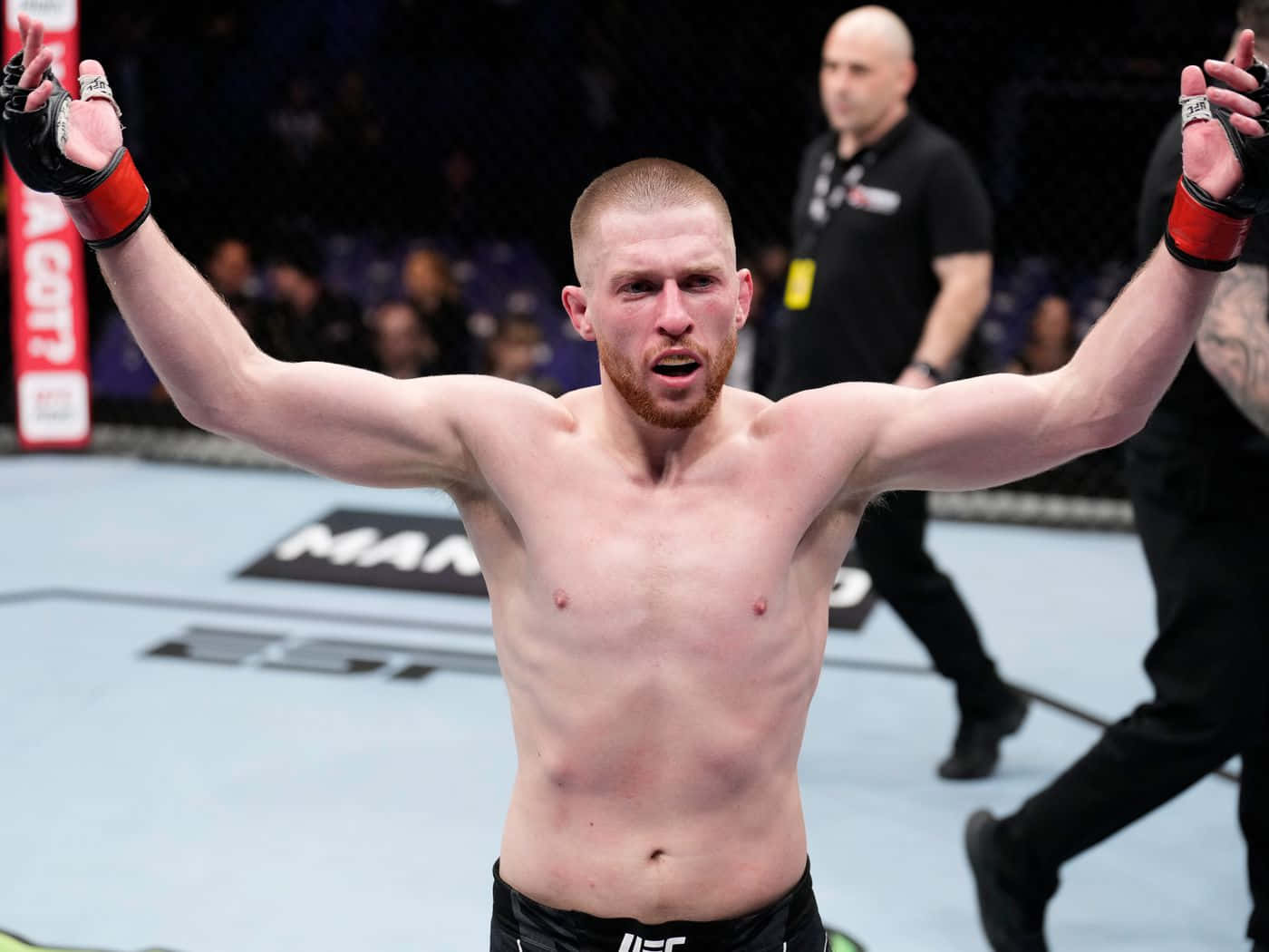 UFC拳手在八角籠內高舉雙臂慶祝勝利。