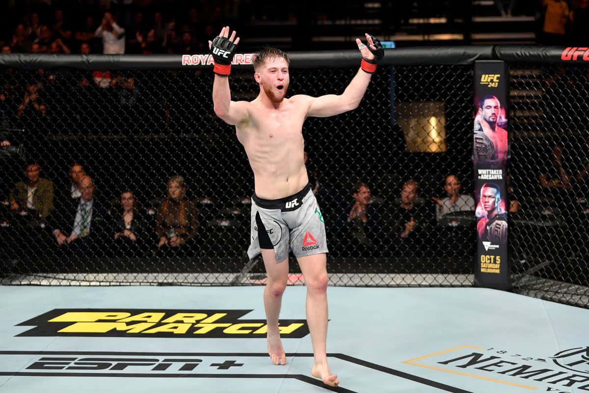 UFC拳手在八角籠內高舉雙臂慶祝勝利。