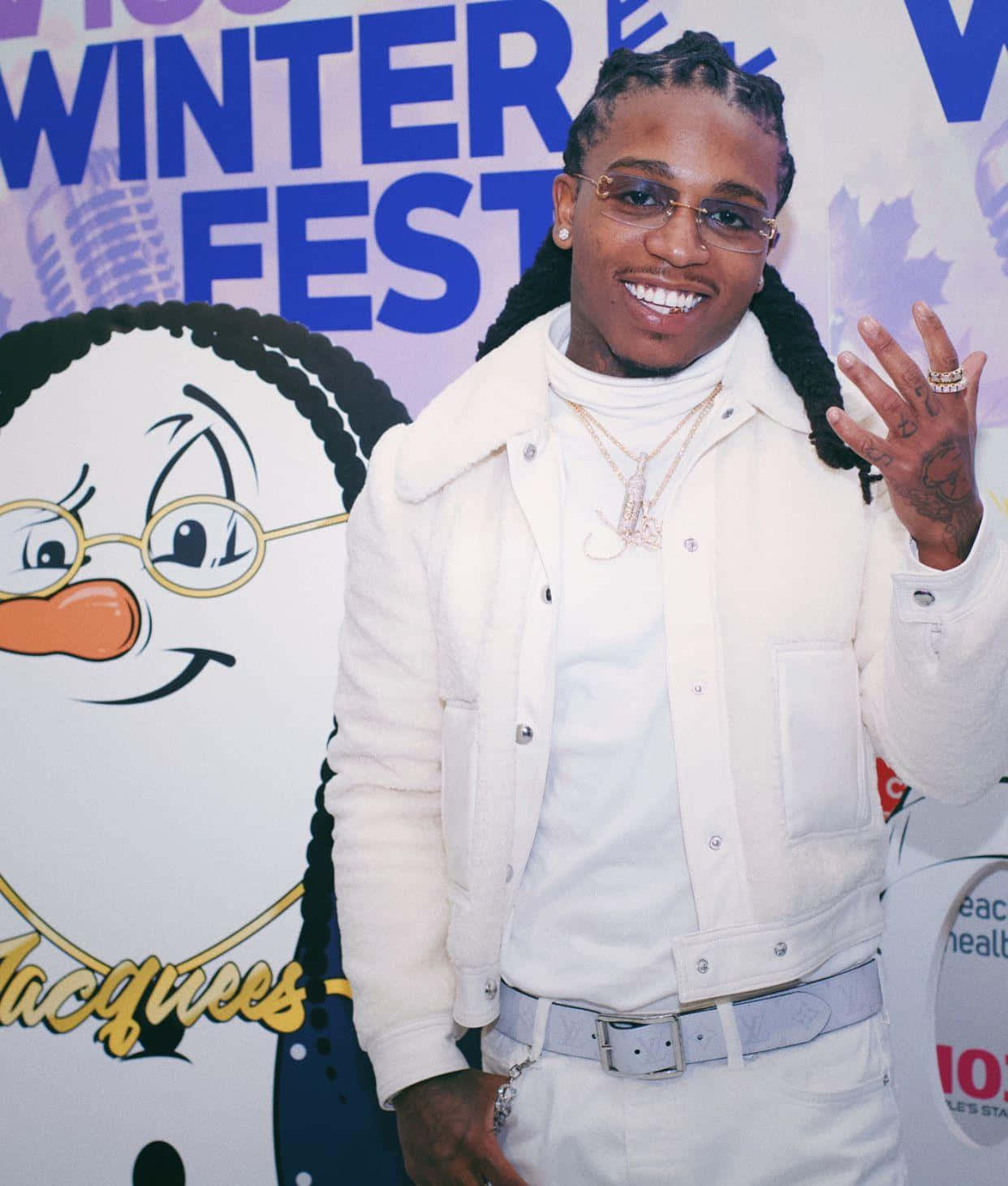 Jacquees 冬日節慶 壁紙 — 一個微笑的男人穿著白色外套在冬季節日背景前揮手，背景有一個卡通雪人。