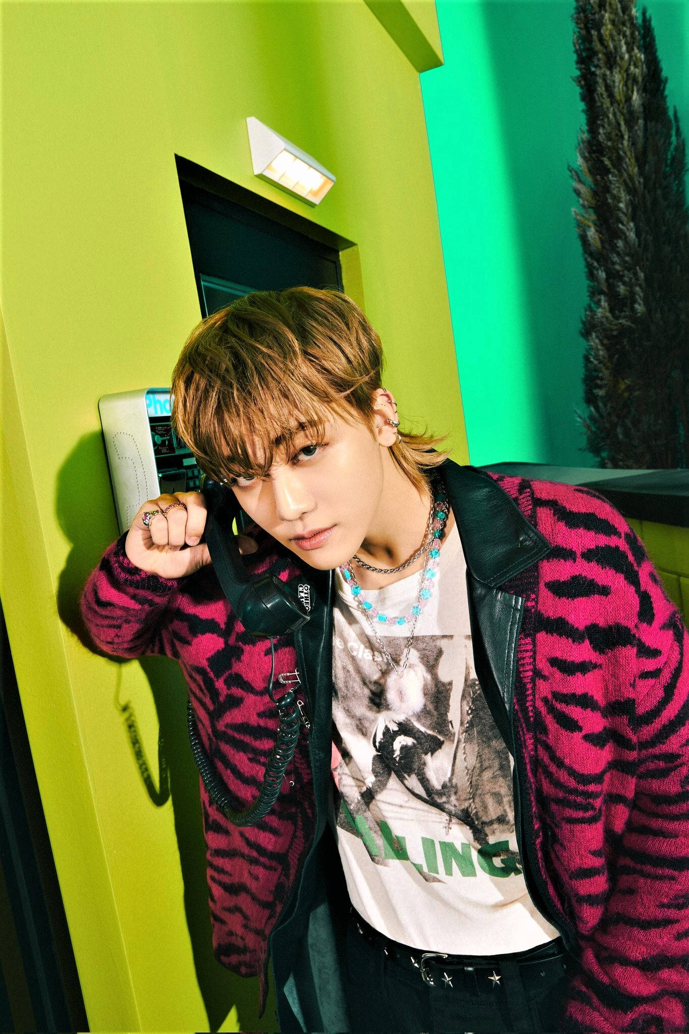 Jaemin NCT 霓虹牆 壁紙 — 一位年輕男子梳著時尚髮型，靠著充滿活力的青檸綠色牆壁，手持復古電話，眼神專注。