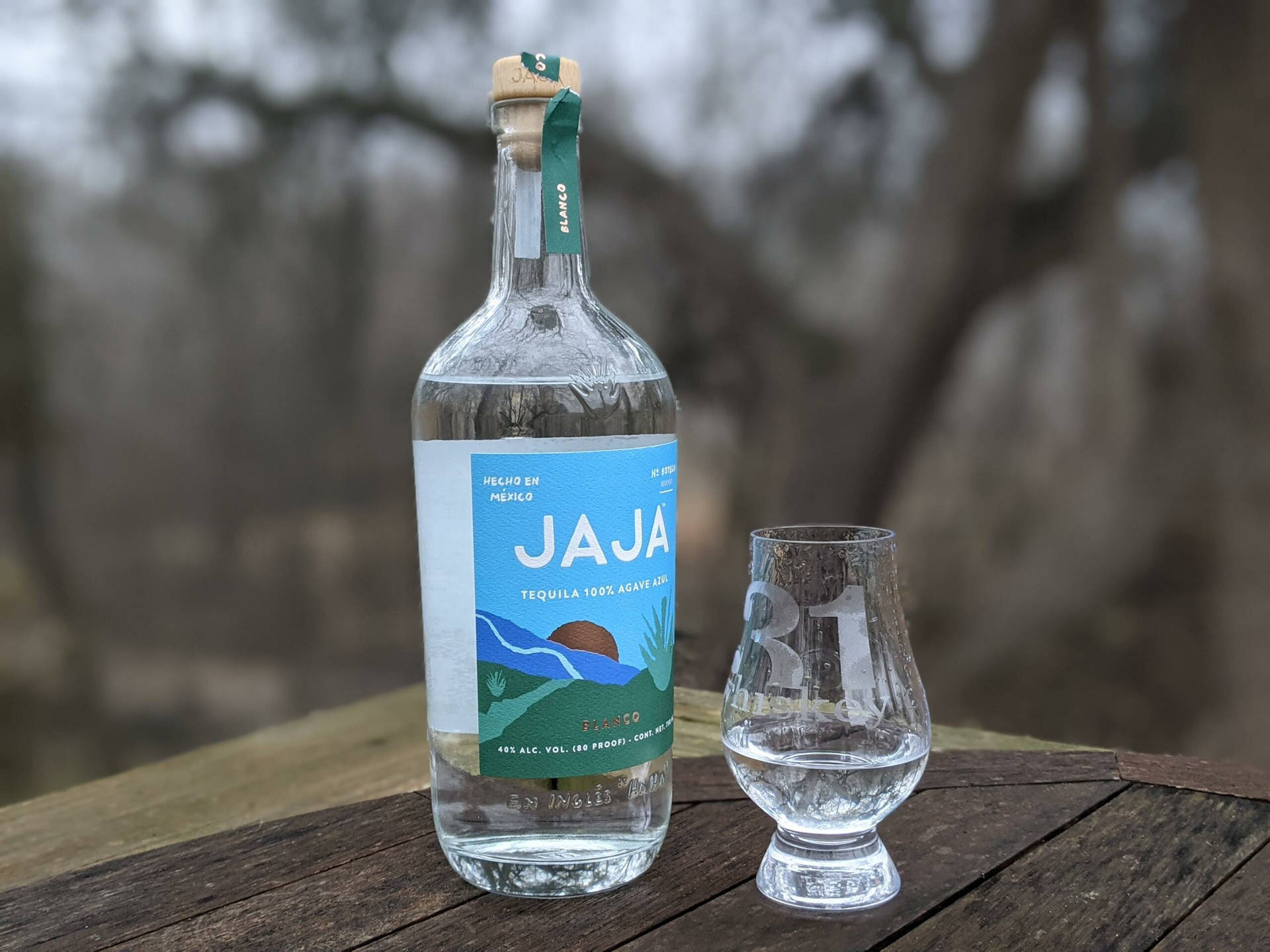一瓶Jaja龍舌蘭酒同品酒杯喺木枱上面。