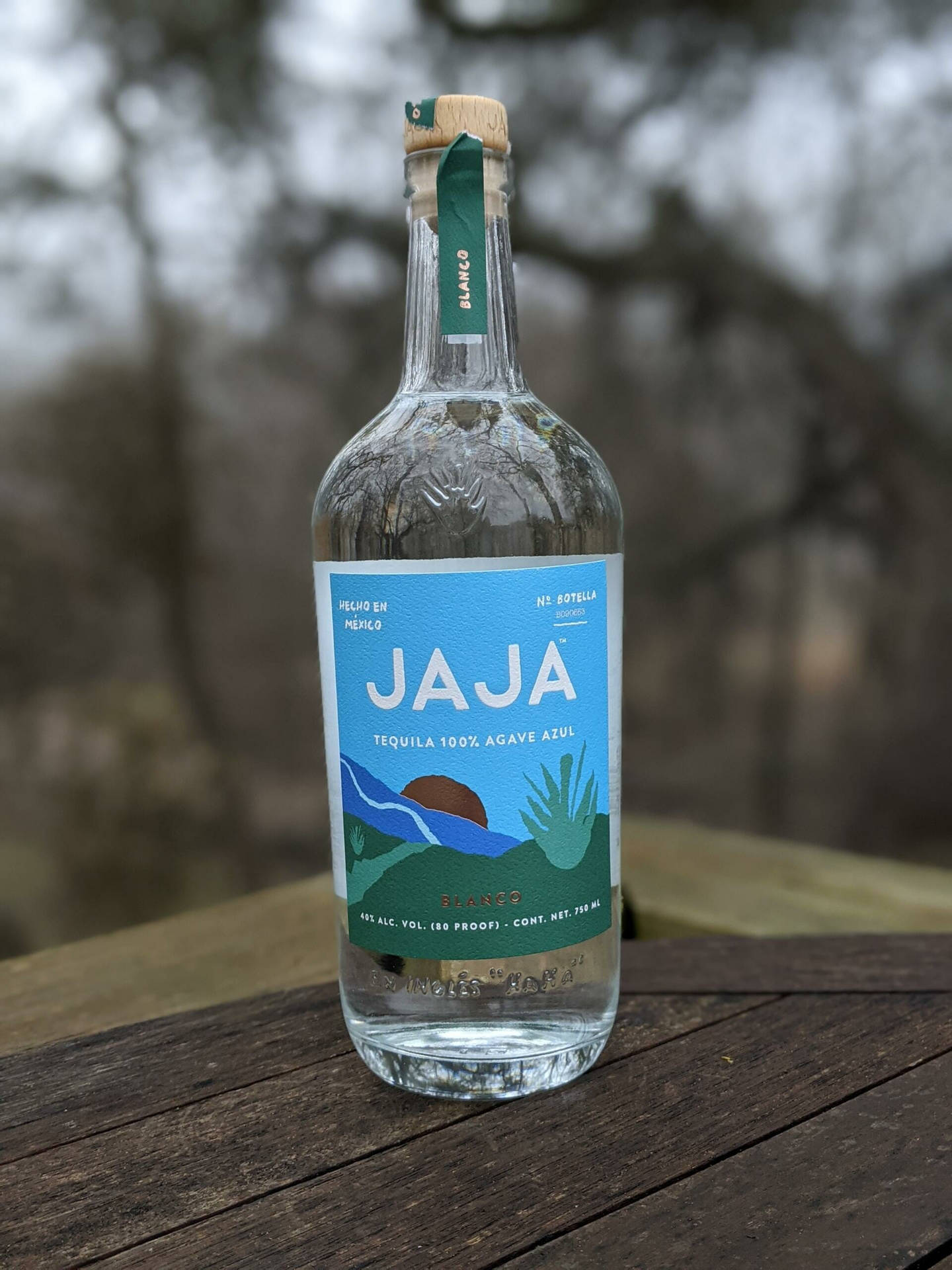 在森林環境中，一瓶Jaja龍舌蘭酒放在木桌上。