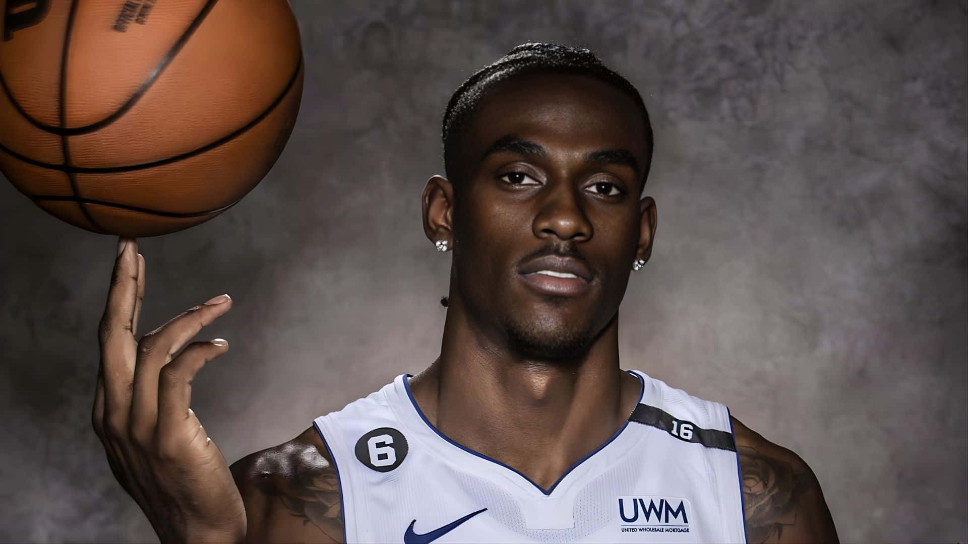 Jalen Duren 籃球專屬肖像 壁紙 — 一個專注的籃球運動員在紋理灰色背景下用指尖平衡一個橙色球。