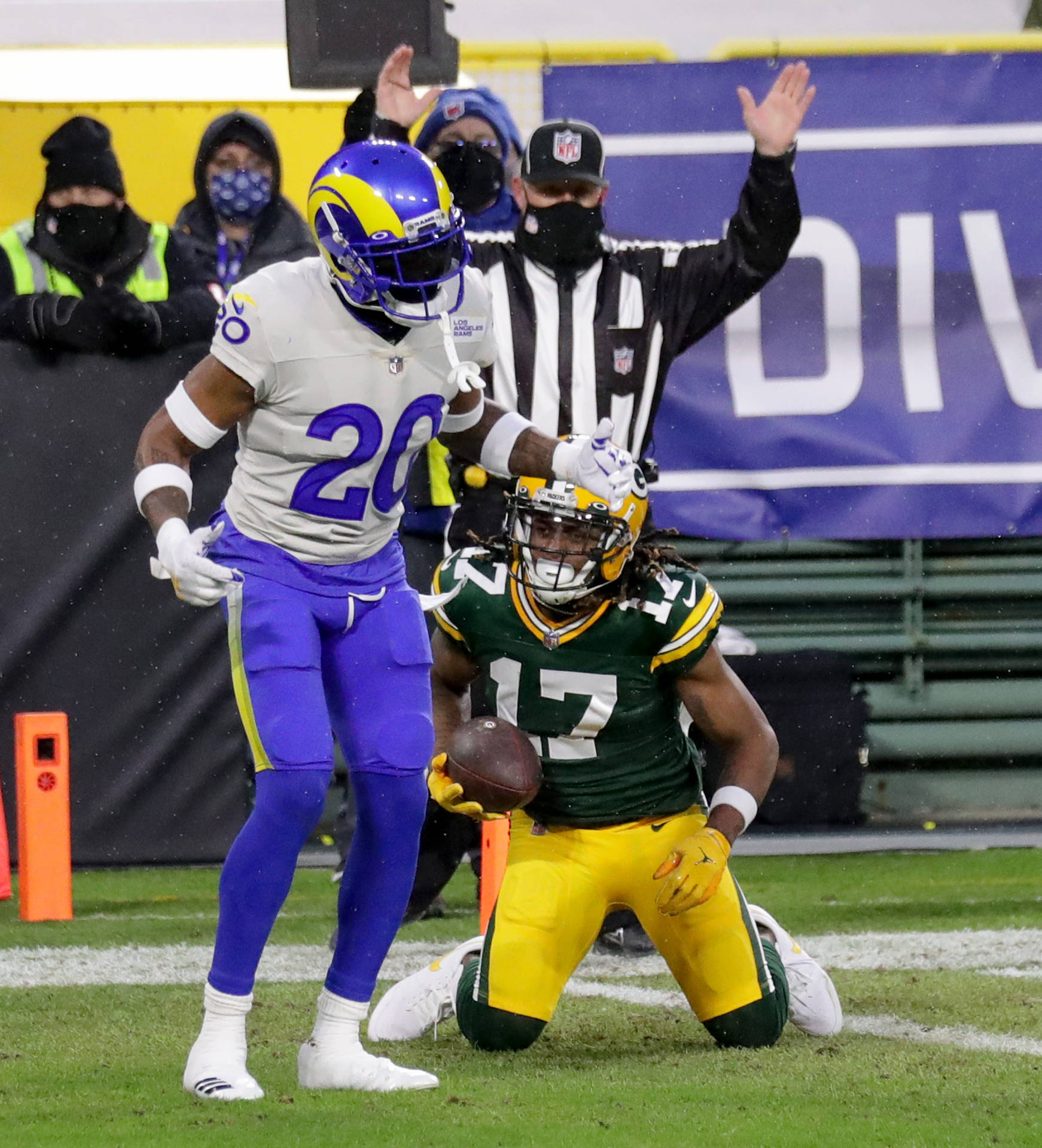 NFL美式足球員跪地持球，對手在雪地球場逼近。