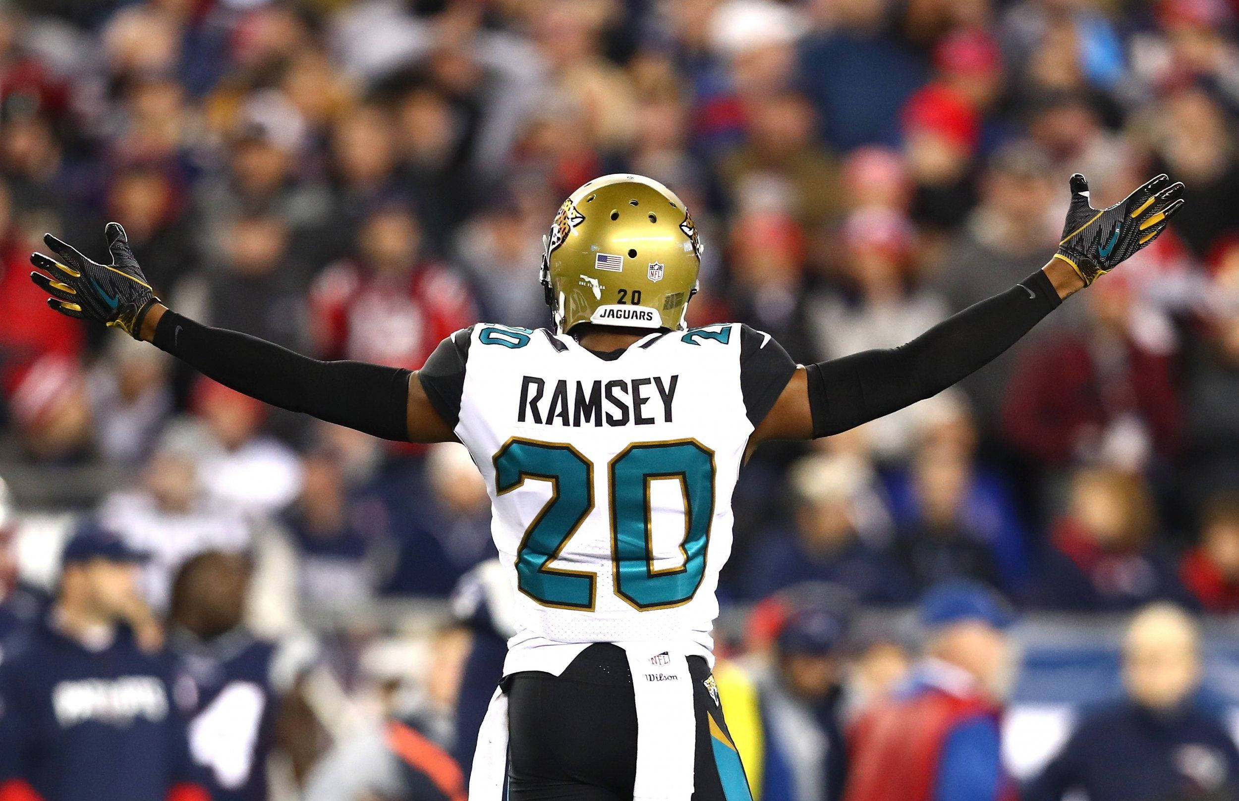 Jalen Ramsey 勝利姿勢 壁紙 — 一名傑克遜維爾美洲虎隊的足球運動員張開雙臂在場上慶祝，背景中球迷歡呼。