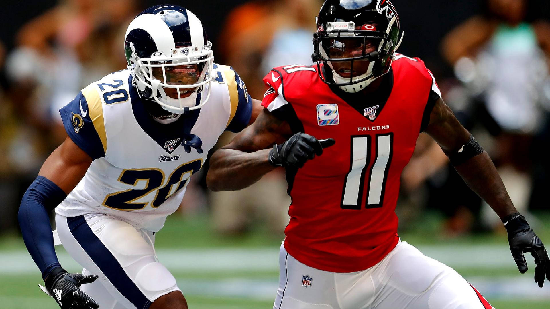 Jalen Ramsey 對戰Julio Jones 壁紙 — 兩名NFL美式足球運動員正在比賽中，一人身穿白色公羊隊20號球衣，另一人身穿紅色獵鷹隊11號球衣，兩人都全神貫注。