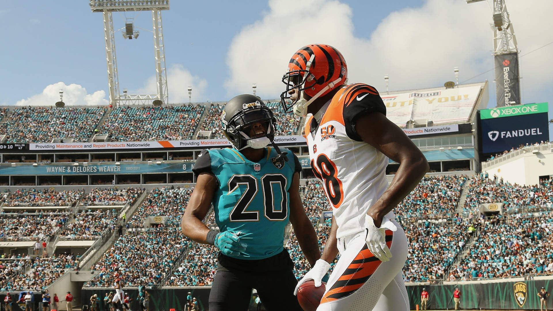 Jalen Ramsey 對決 A.J. Green 壁紙 — 兩名身穿青綠色和橙色球衣的NFL球員在陽光明媚的球場上對峙，身後是座無虛席的體育場看台。