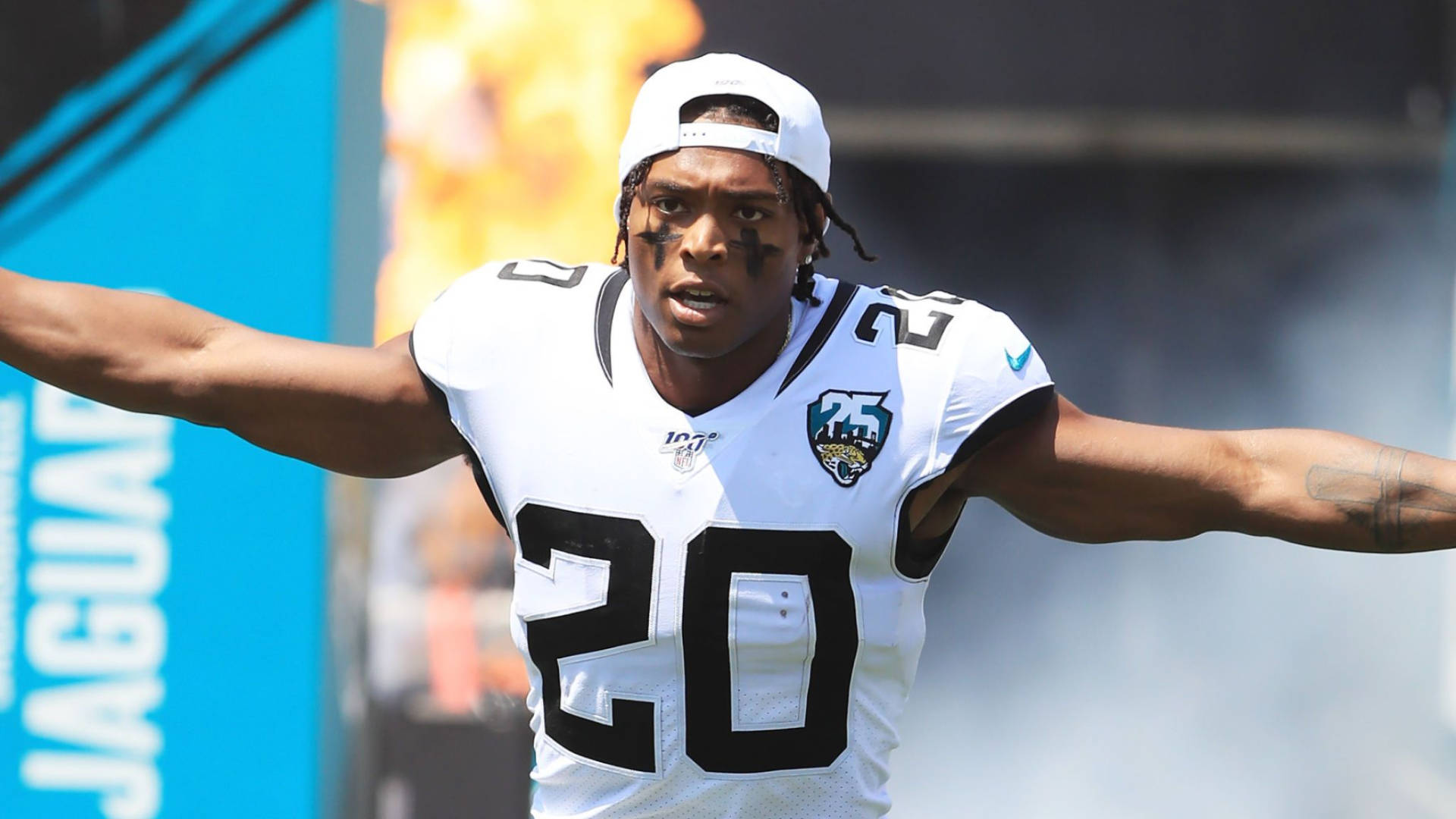 Jalen Ramsey 油彩臉部 壁紙 — 一名身穿白色20號球衣的傑克遜維爾美洲虎隊美式足球員在陽光明媚的球場上張開雙臂慶祝。