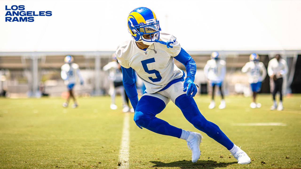 Jalen Ramsey 紅雀隊 5 號 壁紙 — 一名身穿藍色和金色裝備的洛杉磯公羊隊美式足球員在陽光明媚的綠色場地上訓練時動態衝刺。