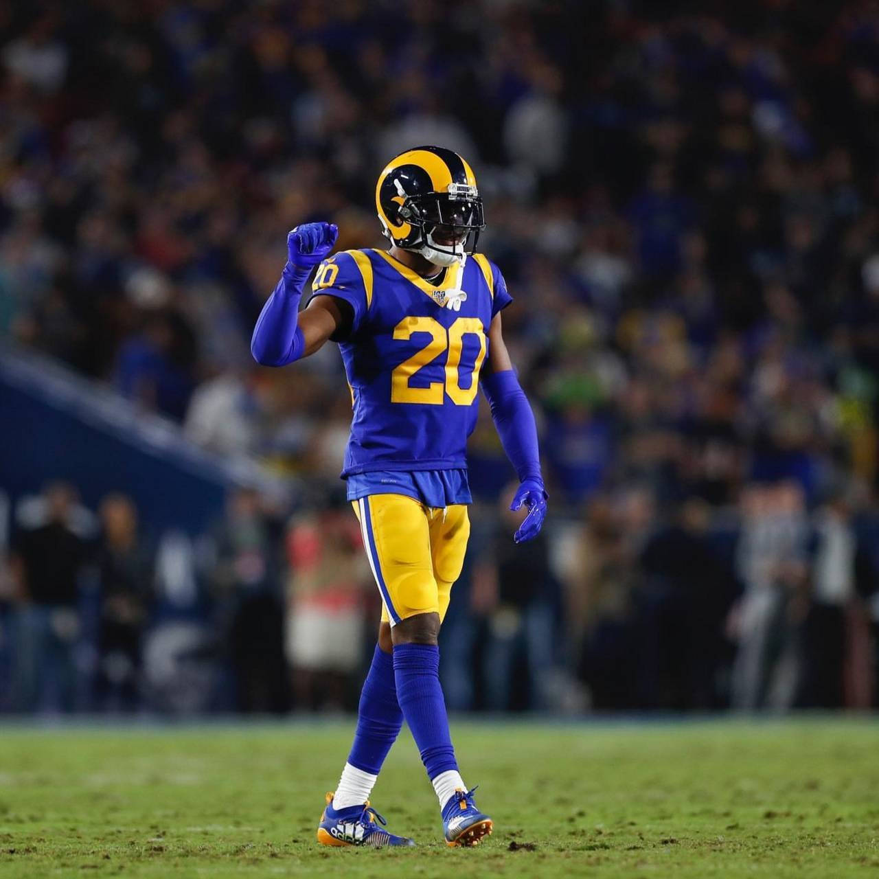 Jalen Ramsey 美國足球運動員 壁紙 — 一名身穿藍金色球衣、背號20的美式足球員在燈光球場上慶祝，背景是模糊的體育場人群。