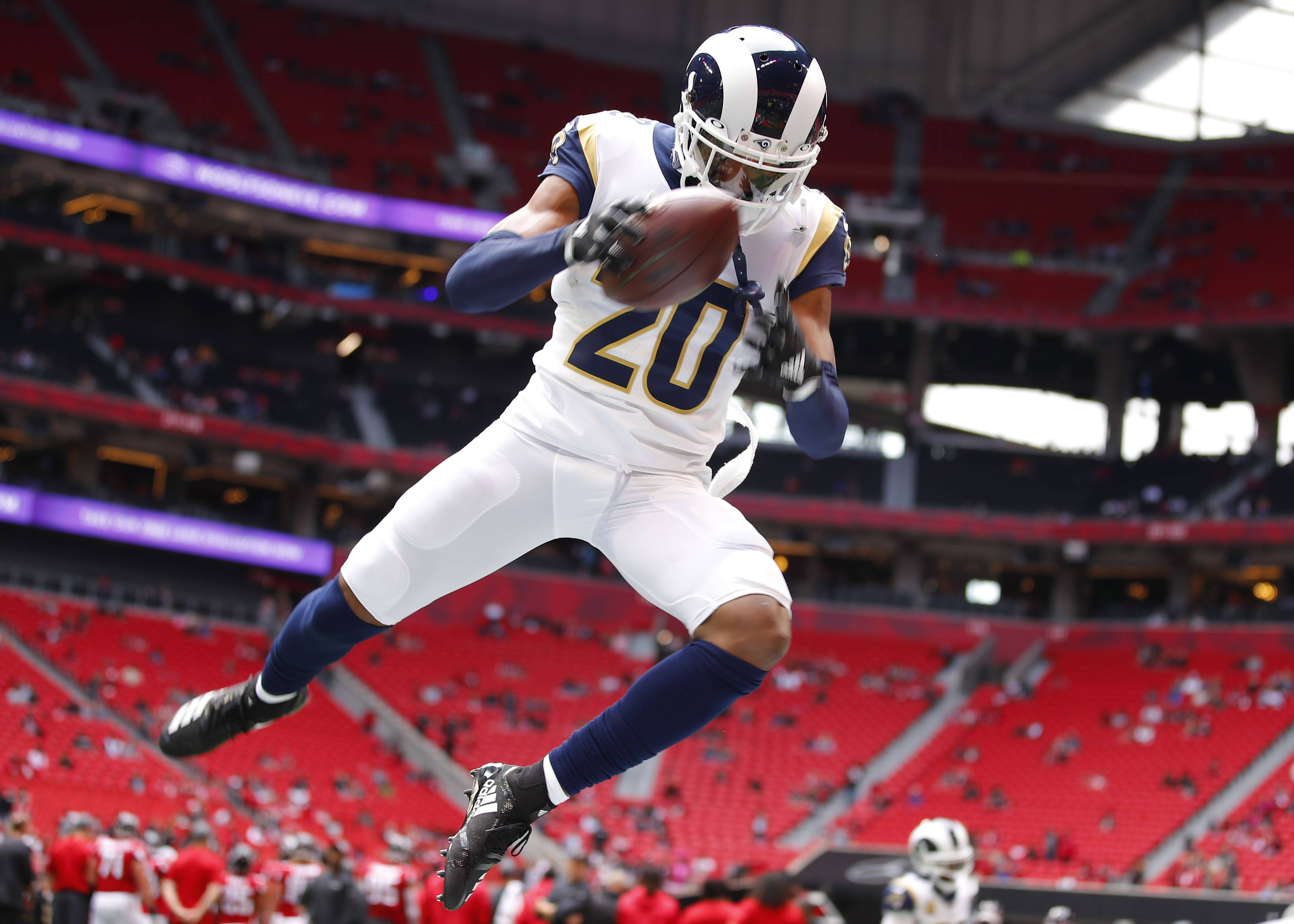 Jalen Ramsey 高跳瞬間 壁紙 — 一名身穿白色球衣的足球運動員在紅色座位的體育館內跳起接球。