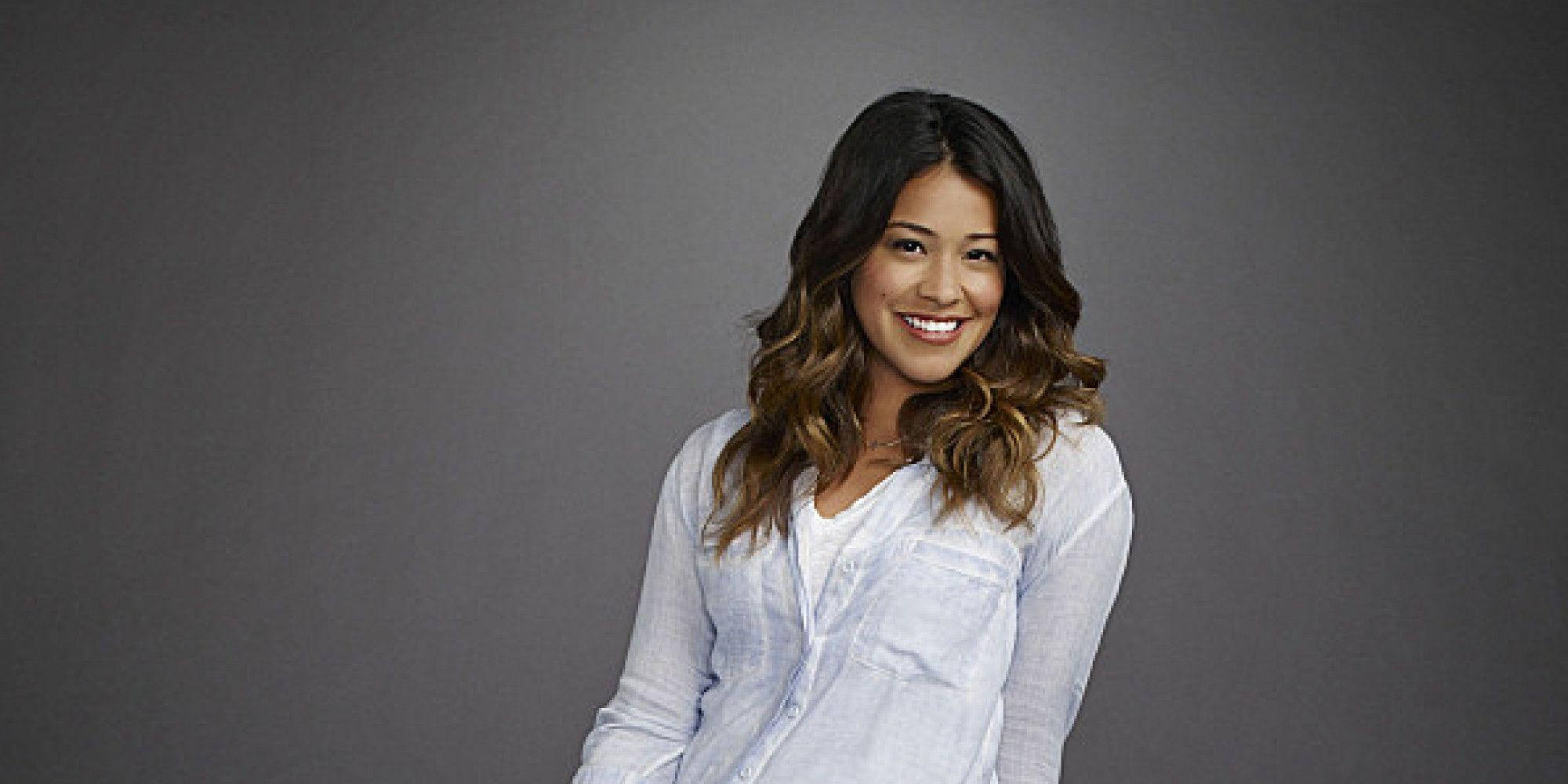 《Jane the Virgin》中的強韌Jane 壁紙 — 一位微笑的女士，波浪形深色頭髮，穿著淺藍色鈕扣襯衫，背景是純灰色攝影棚。