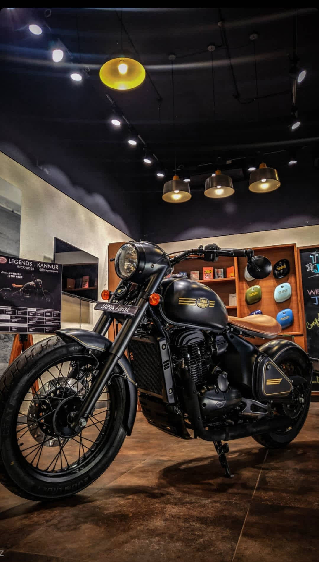 黑色 Royal Enfield 摩托車在現代室內展廳中展示，配有溫暖的燈光和木架。