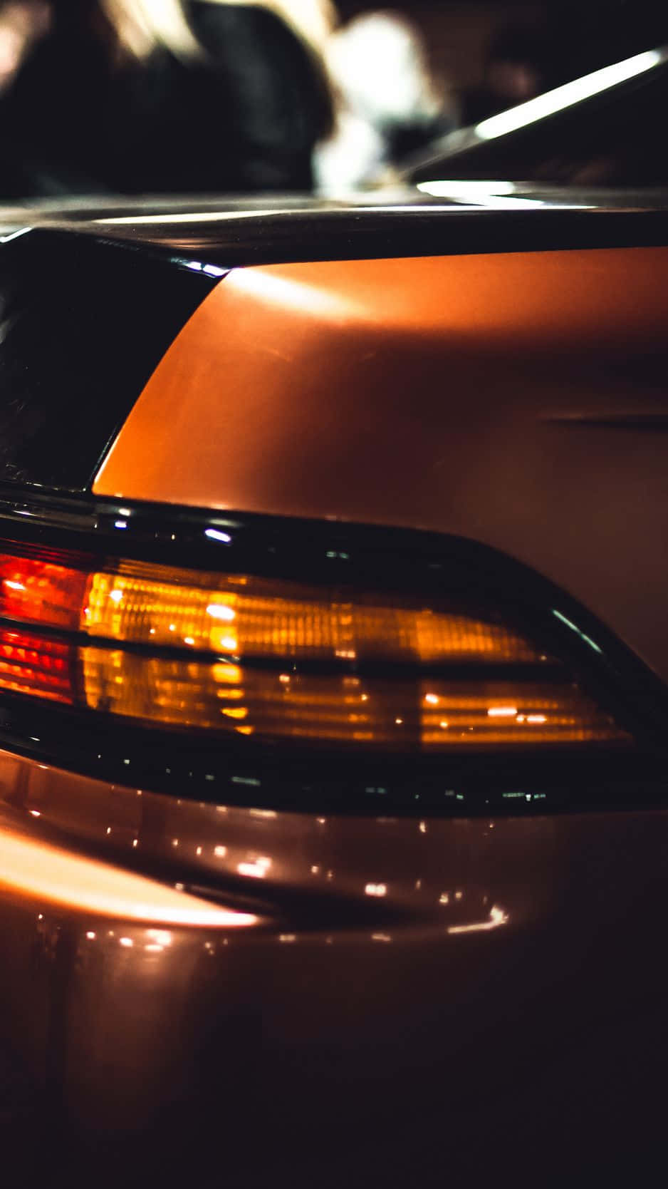 汽車琥珀色尾燈在夜間反射城市燈光的特寫。
