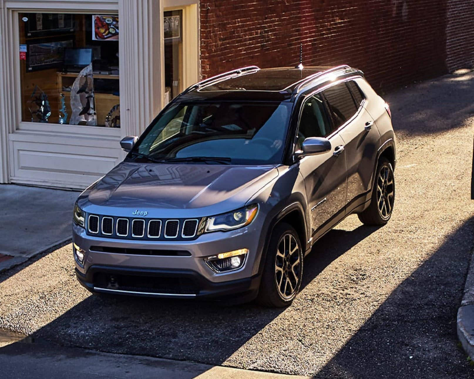 銀色Jeep Compass停泊在城市街道上，背景是磚砌建築。