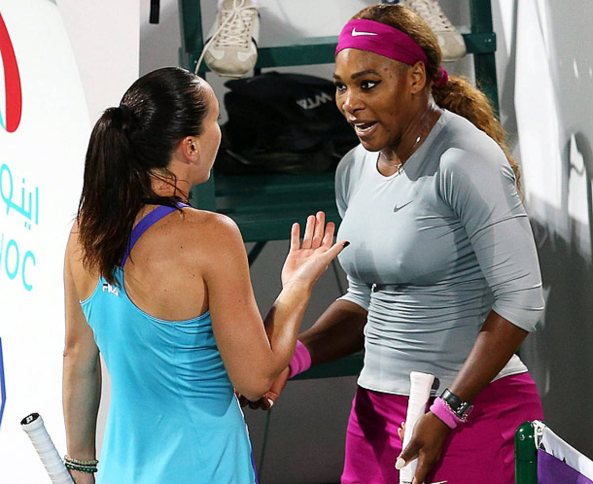 Jelena Janković與Serena Williams 壁紙 — 兩名女網球運動員在球場上友好地擊掌，穿著鮮豔的運動服和可見的裝備。