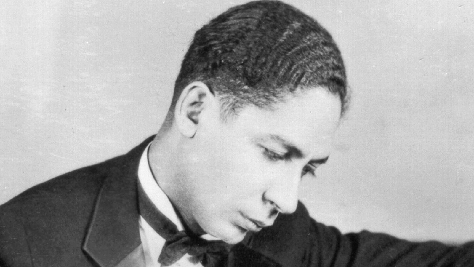 Jelly Roll Morton — 哥倫比亞爵士樂的革新者 壁紙 — 一位身穿西裝和領結的年輕男子，低頭沉思的黑白肖像。