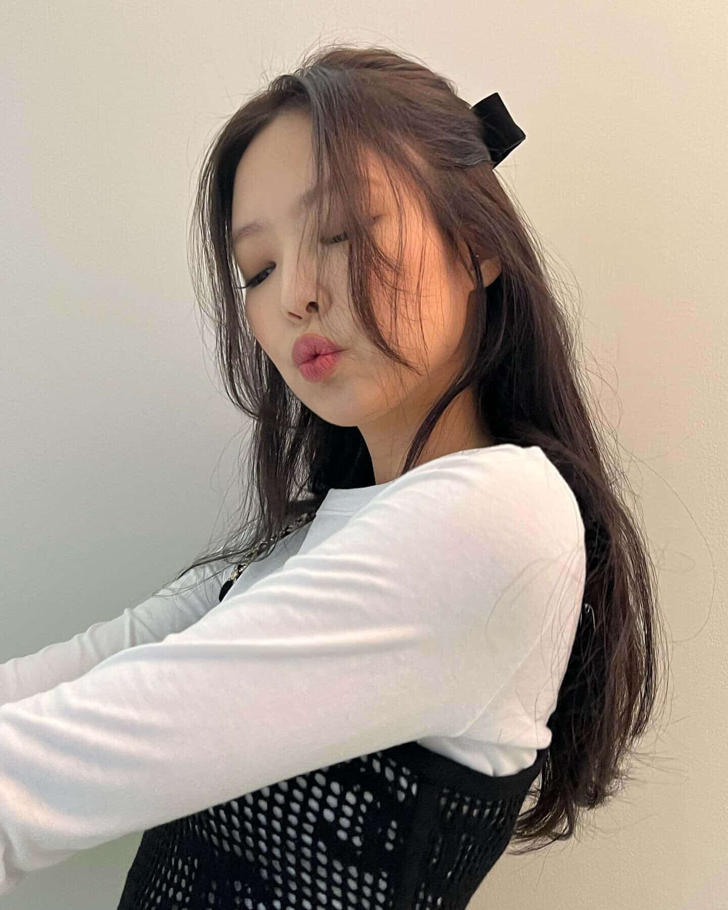 Jennie BLACKPINK 嘴脣嘟嘟親吻表情照 壁紙 — 一位長黑髮、戴黑色蝴蝶結的年輕女性，穿著白襯衫和黑色網眼上衣，嘟起嘴唇。