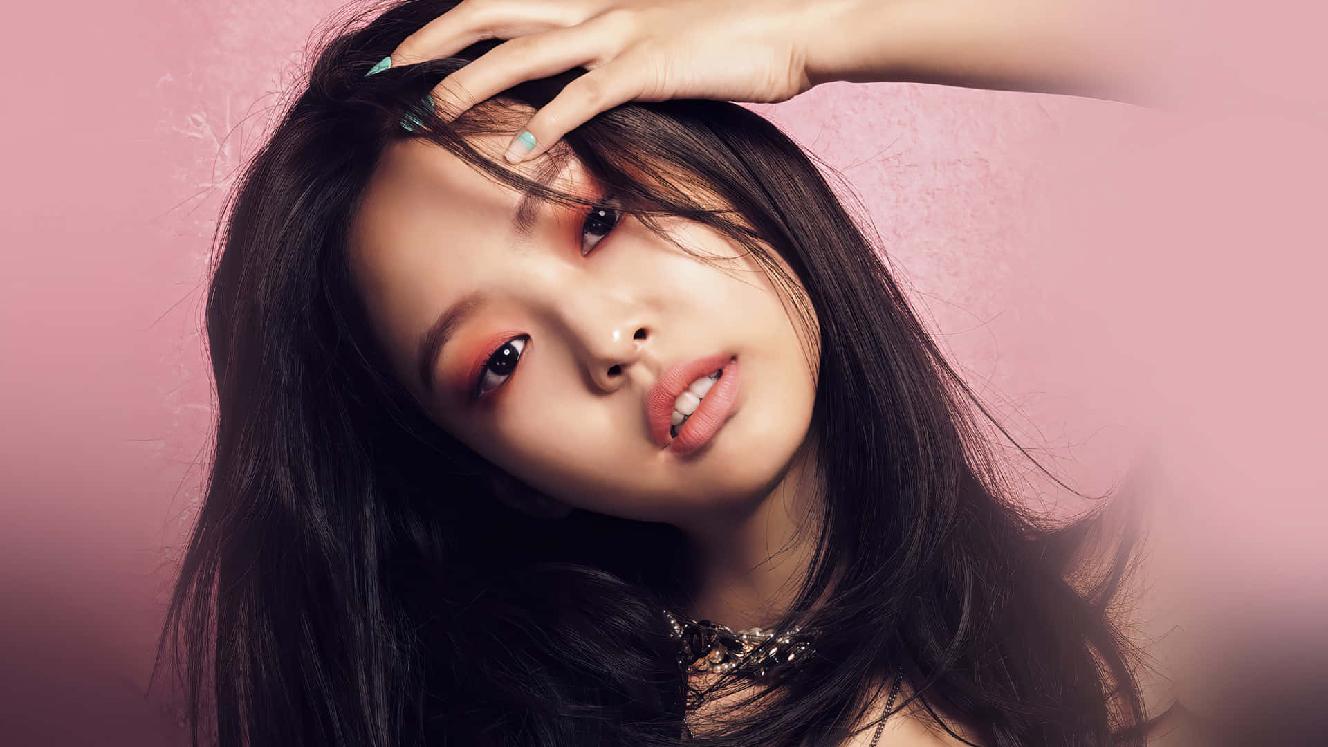 Jennie Kim 傾頭甜美照 壁紙 — 一位深色頭髮、妝容大膽的年輕女性，在柔軟的粉紅色紋理背景上凝視著。