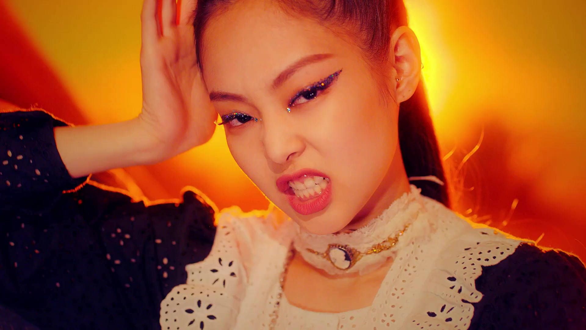 Jennie Kim 她的 Sheesh 姿勢 壁紙 — 一位年輕女性，化著大膽妝容，在熾熱的橙色燈光下，一手放在頭髮上，擺出強烈的姿勢。