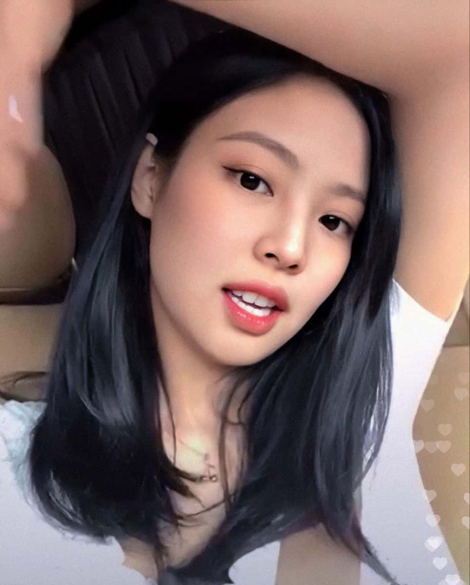 Jennie Kim 的甜美自拍照 壁紙 — 一位長黑髮的年輕女性微笑著靠在汽車座椅上，雙臂舉起。