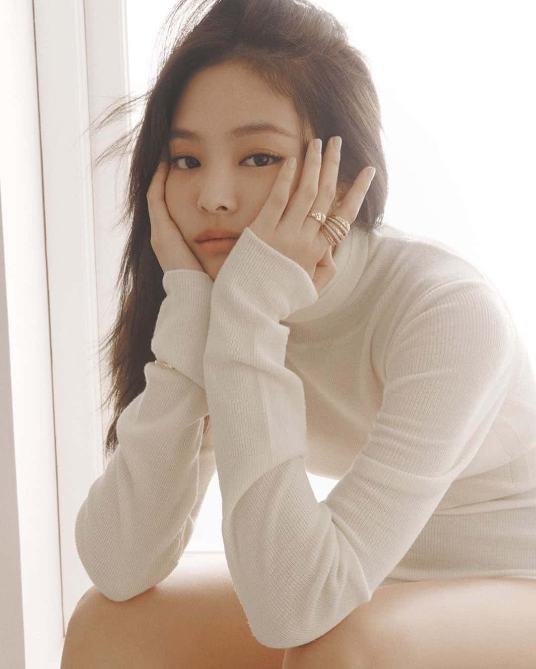 Jennie Kim 穿白色毛衣的溫馨照 壁紙 — 一位身穿白色羅紋毛衣的女性坐在明亮的窗邊，雙手托腮，目光沉思。